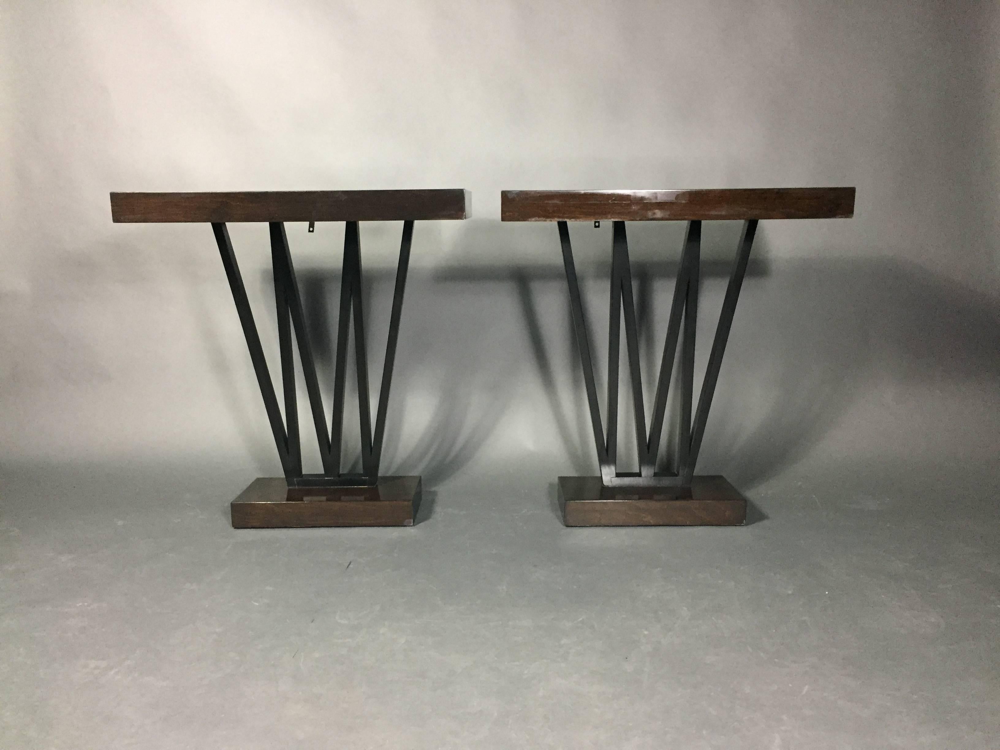 Firmly in the Art Deco tradition pair of console tables in dark stained and lacquered wood, each with a set of three V-shaped supports, USA, 1930s. Slight wobble to one table - both have a newer I-hook underneath at back to attach to wall for