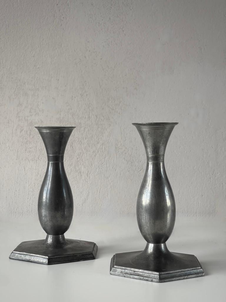 Questi rari candelieri Art Deco degli anni '20, dalle forme eleganti, sono opera del famoso scultore e metallurgico danese Just Andersen. Noto per il suo uso innovativo dei materiali, Andersen ha creato questi candelieri in peltro, un materiale che