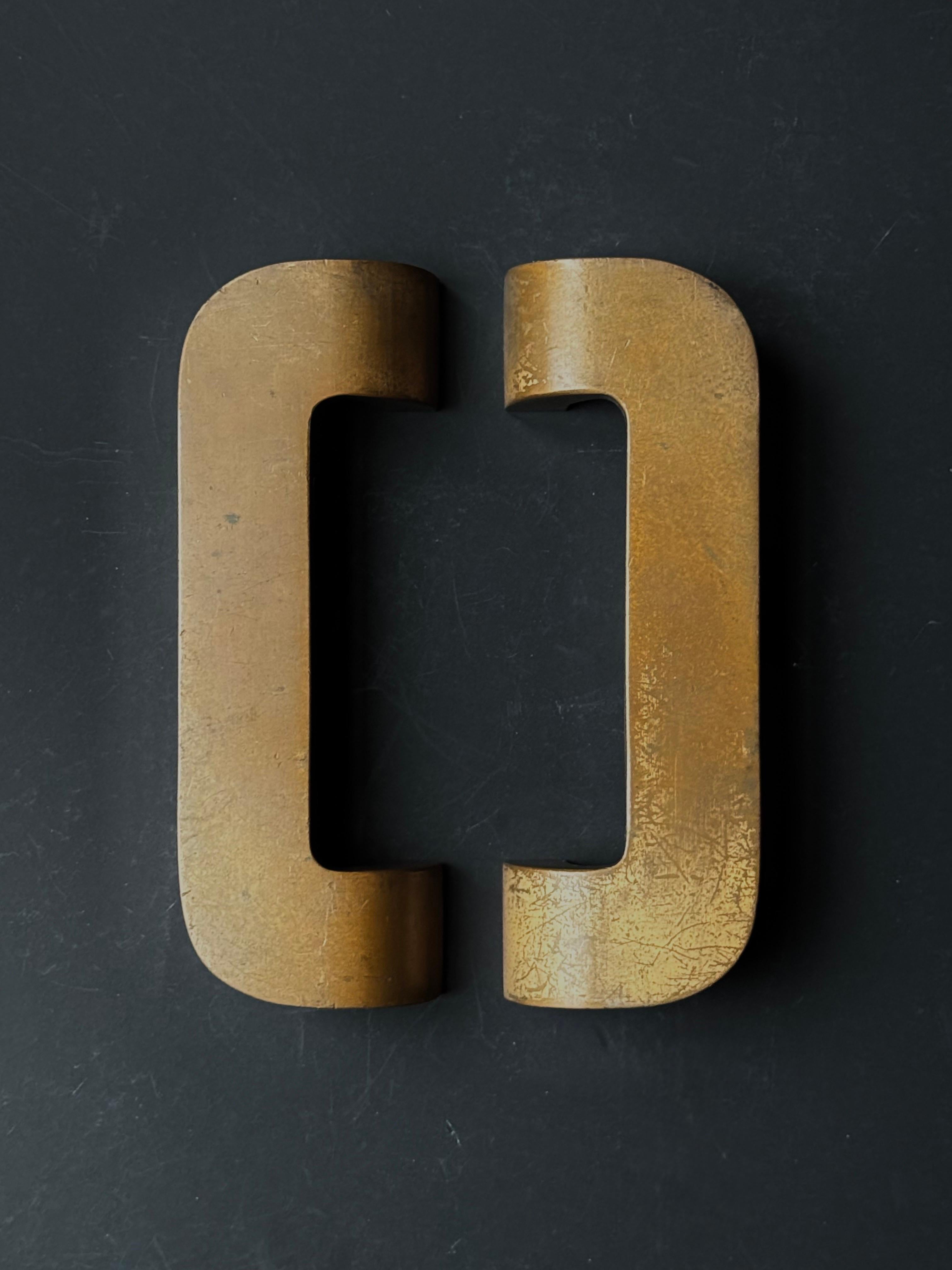 Un par de manillas pesadas de bronce fundido. En estilo art déco, siglo XX.  

Un elegante diseño táctil, con la barra plana principal de unos 8 mm (1/3
