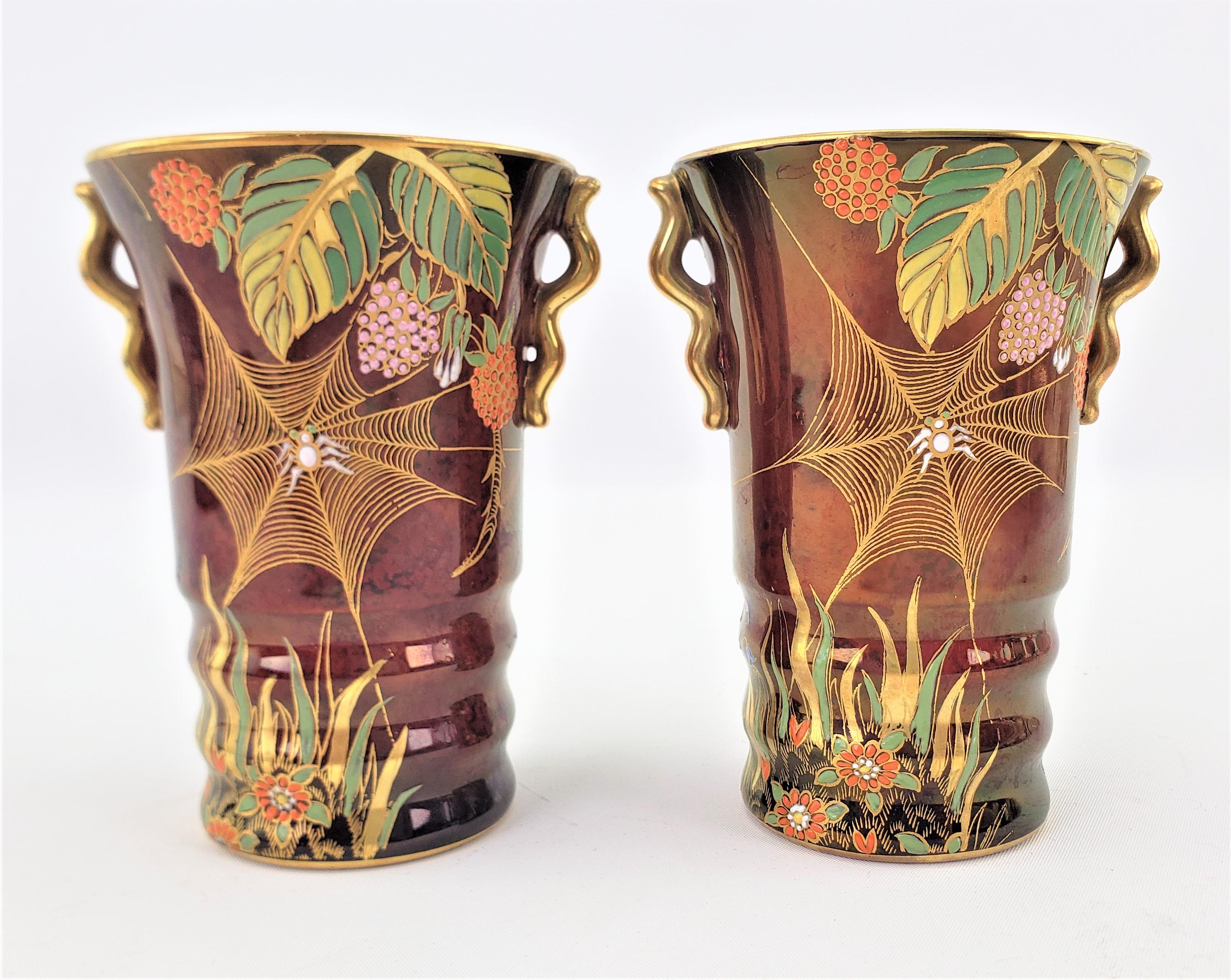 This pair of Art Deco porcelain and ornately hand-painted vases were made by the well known Carlton Ware factory of England, in approximately 1920 in a period Art Deco style. The vases are done in their line of Rouge Royale with a deep red ground