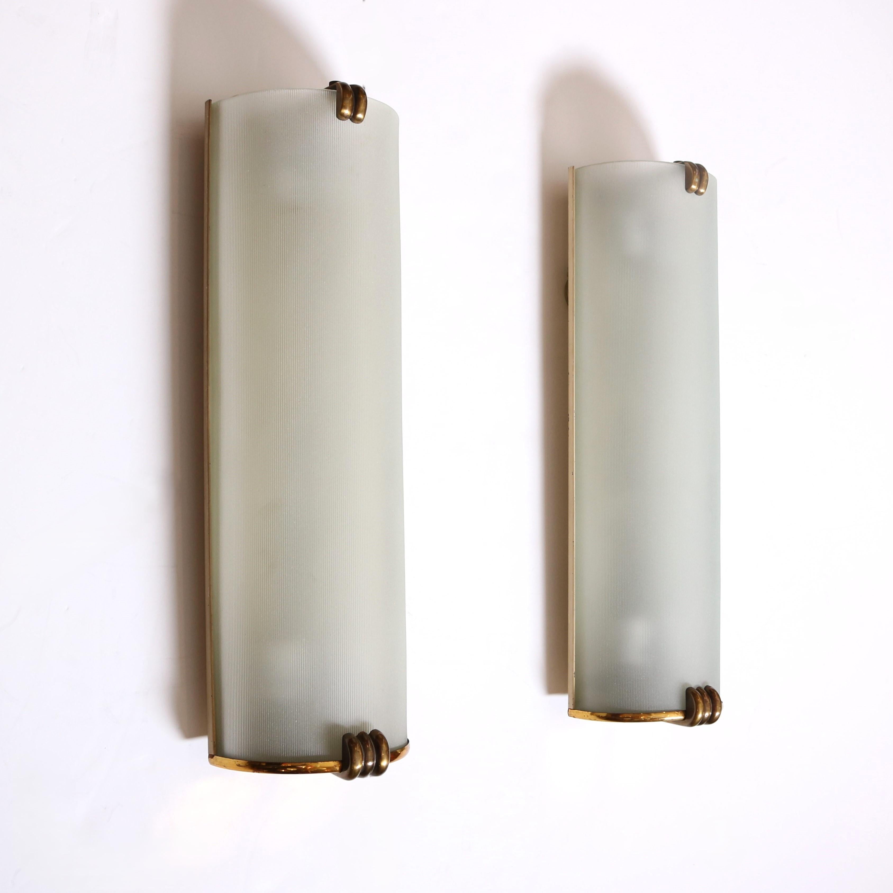 A beautiful pair of period Art Deco Sconces with stylized brass accents.  Finely ribbed and frosted glass shades mounted on a brass backplate.   The semi-circular form and stylzed fleur style mount exemplify the period. Wired for the US market,