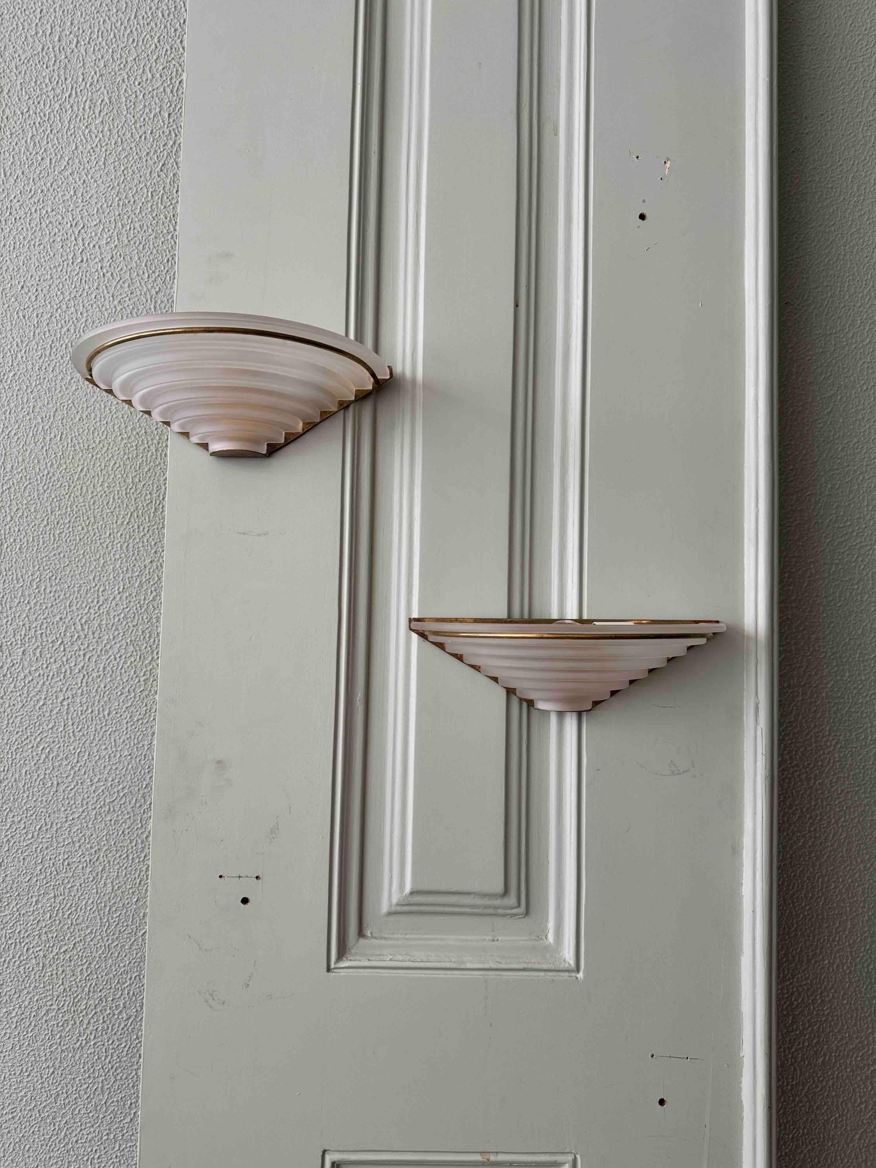 Presenting a stunning pair of Portuguese Art Deco Sconces from the 1940s, these exquisite pieces are a true testament to timeless design and craftsmanship. Designed and produced in Portugal, each sconce features a beautifully frosted, step-shaped