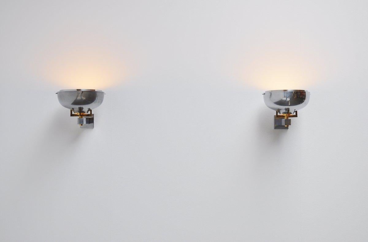 Fantastic pair of uplighter sconces in the manner of Jean Perzel, France, 1940. These lamps are made of nickel-plated metal and have brass details. They have some very nice details and are in original condition. Give very nice light when lit. Easy