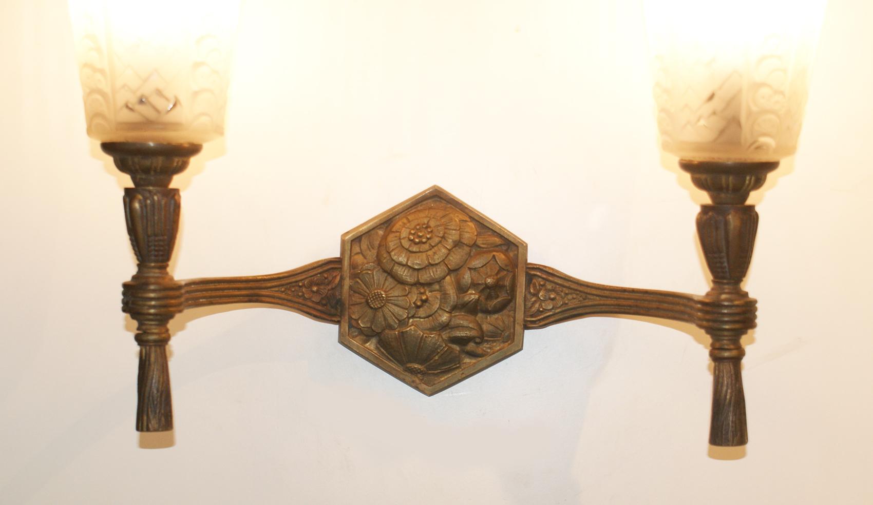 Stunning pair of French Art Deco wall lights consists of patinated bronze structure with beautiful floral motif design in the central of the sconces and two arms of lights supporting two tulips in molded clear frosted glass, signed Muller freres