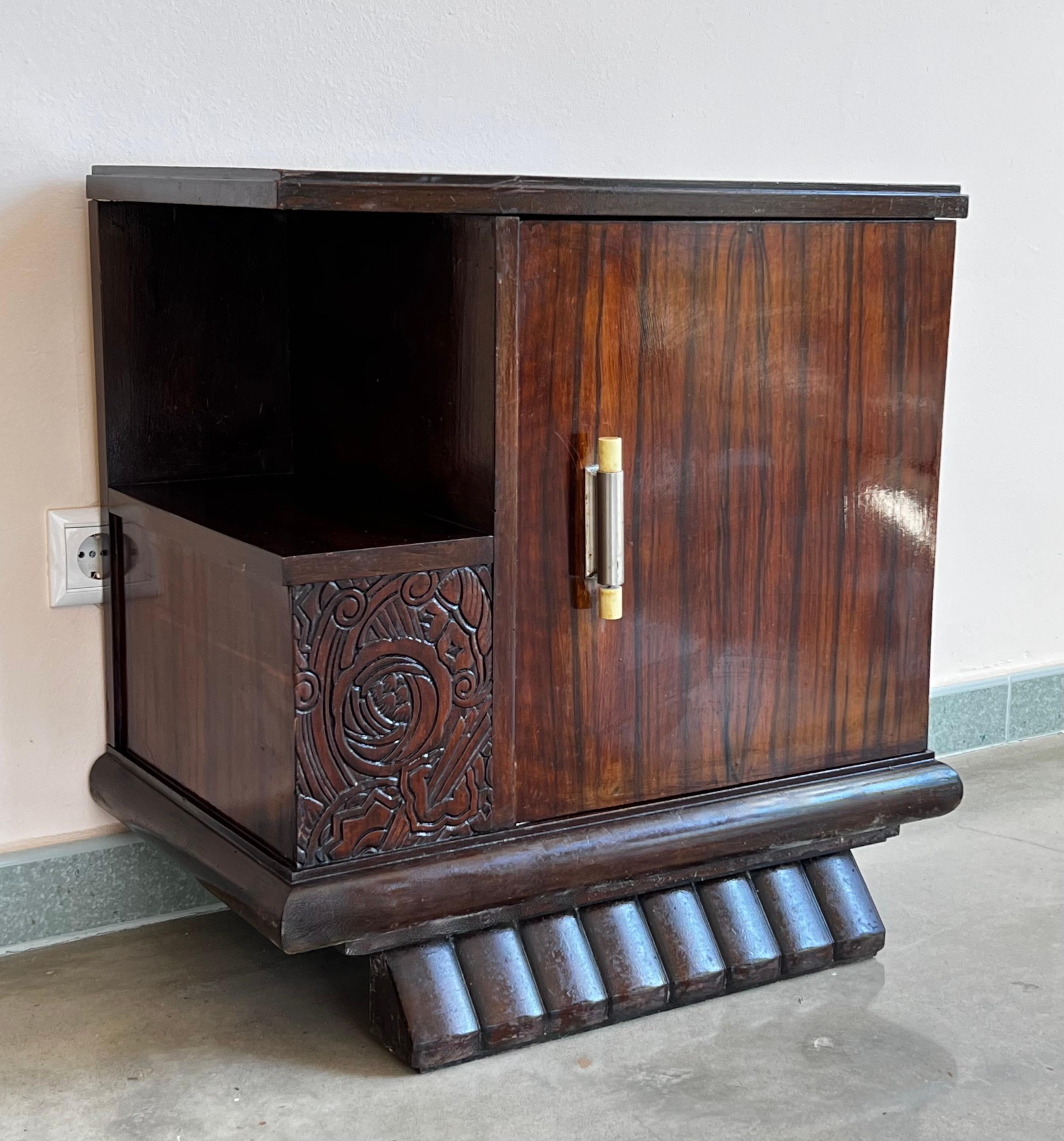 This pair of circa 1930s French Art Deco side cabinets could be used to flank a sofa or as nightstands. Each has a storage compartment with hinged door and narrow open shelves at the sides. One interior drawer and one ceramic box. Cabinets are set
