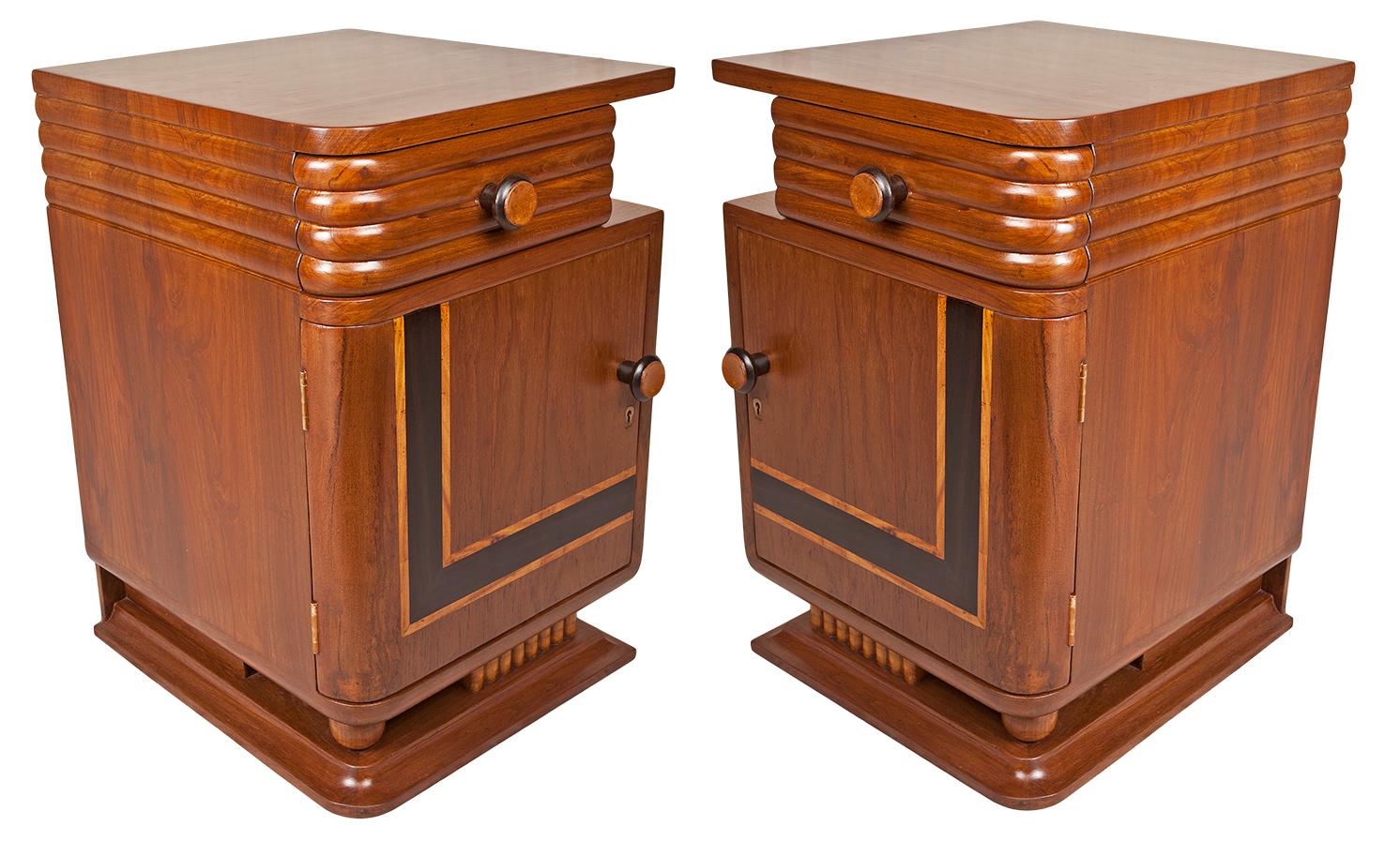 A pair of opposing Art Deco side table cabinets. Teak with rosewood and birch inlay. Reeded front drawer, cabinet with lock and key and interesting ball and carved details at the base. These would even look great pushed together to make a low