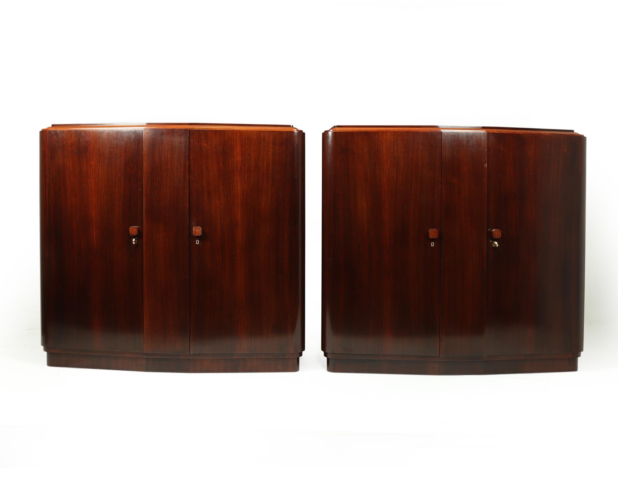An identical pair of high quality sideboards in rosewood, (one sideboard has drawers behind) with slightly shaped fronts shaped wooden handles and lockable doors, doors open to reveal shelves behind one key with each sideboard

Age: 1930

Style: