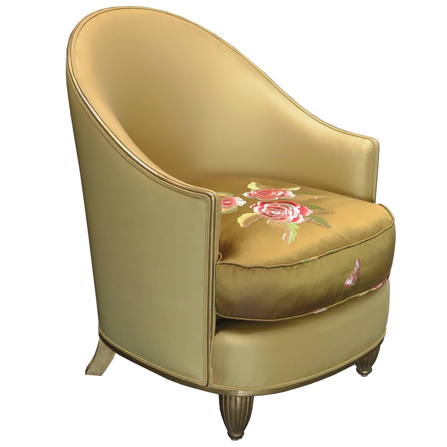 Beautiful pair of Art Deco lounge chairs with a curved frame in antiqued gold leaf. Chairs are upholstered in olive silk, the dark olive seat cushions have hand embroidered floral details. Gold leafed front legs have a ribbed design.