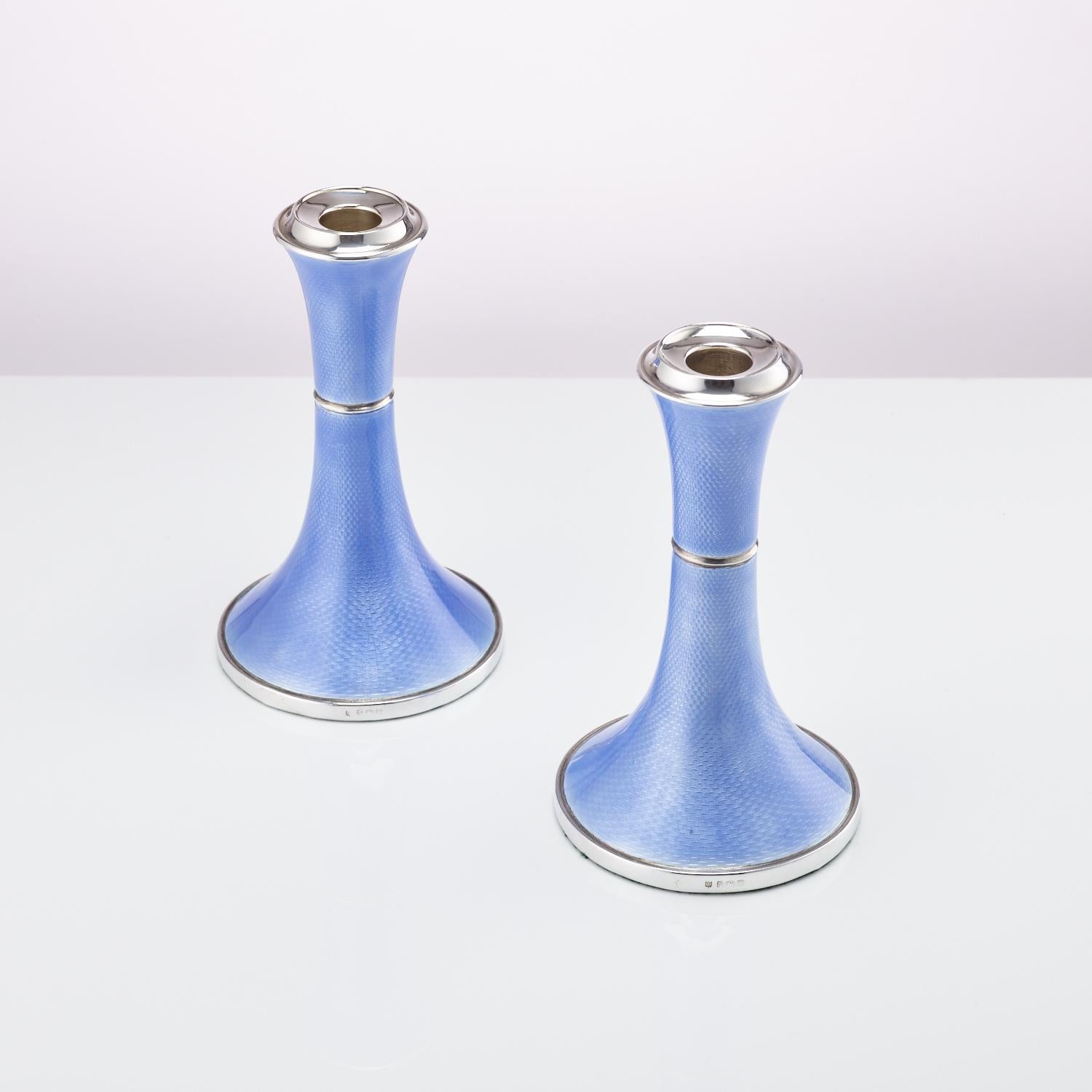 A beautiful pair of Art Deco silver and guilloche enamel candlesticks. The enamel is a stunning blue which flows around the shape of the base up to the top. 
They are a good size and very aesthetically pleasing. 
Origin: Birmingham, England,