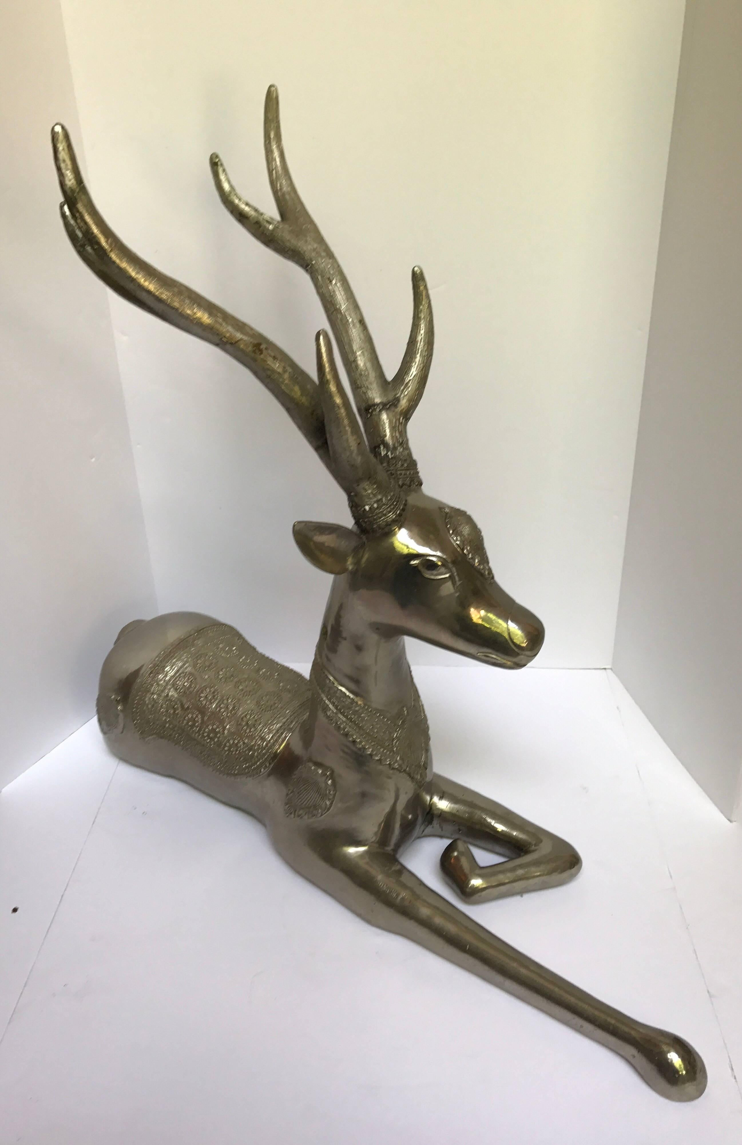 Unique and very large pair of Hollywood Regency silvered bronze deer statues. Both have a hammered design that covers their body.