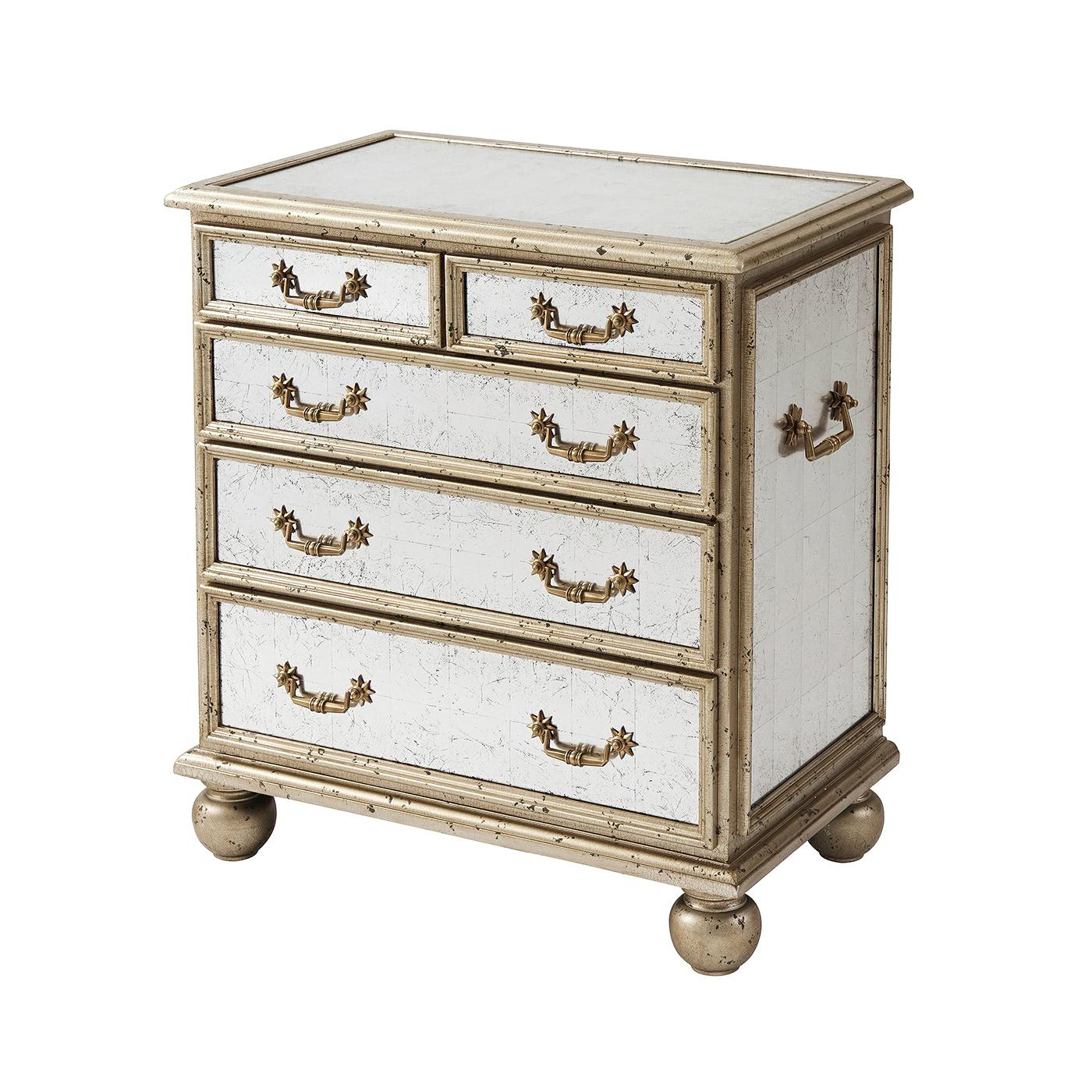 An Art Deco style silver leaf and antiqued trellis hand mirrored bedside chest of drawers, the rectangular mirror paneled top above two short and three long drawers fitted with brass handles, on bun feet. 
Dimensions: 27.25