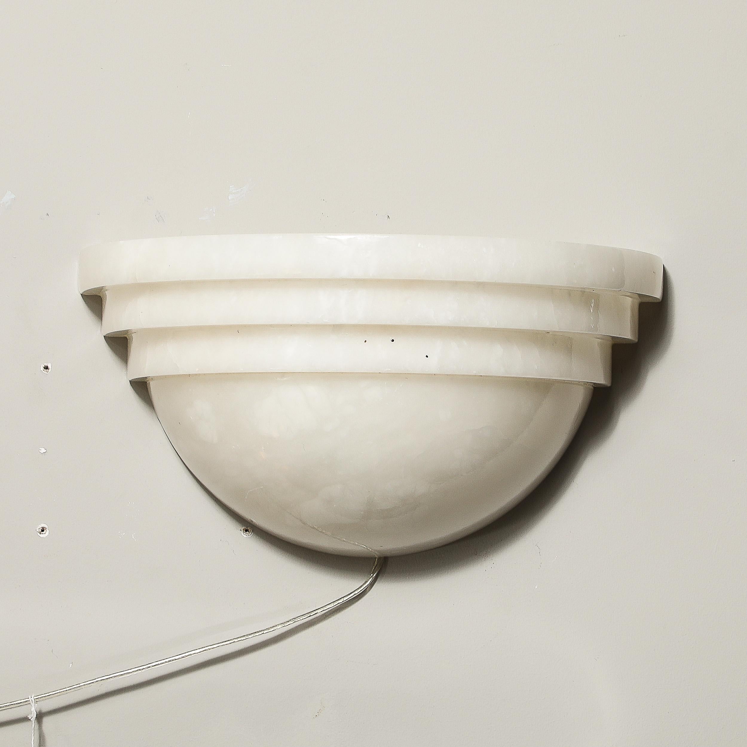 Dieses elegante und schön geformte Paar Alabaster-Wolkenkratzer im Art-Déco-Stil stammt aus dem Frankreich des 20. Jahrhunderts. Die Schirme bestehen aus massivem, geschnitztem Alabaster mit einem geschwungenen unteren Teil, der zu drei