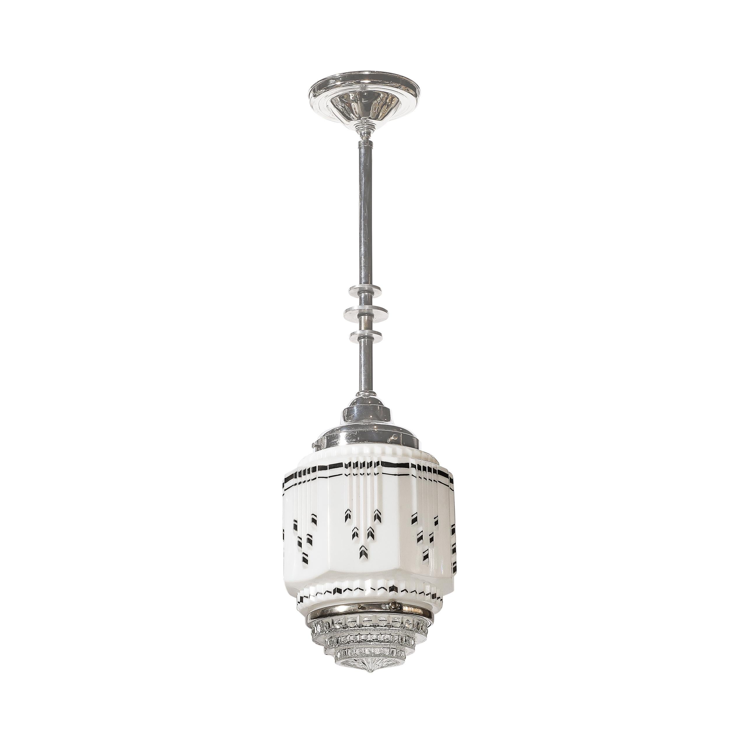 This beautiful and materially exquisite Pair of Art Deco Skyscraper Style Milk Glass Pendant Chandeliers with Black Enameled Detailing & Chrome Fittings originates from the United States, Circa 1935. They features a timeless geometric composition