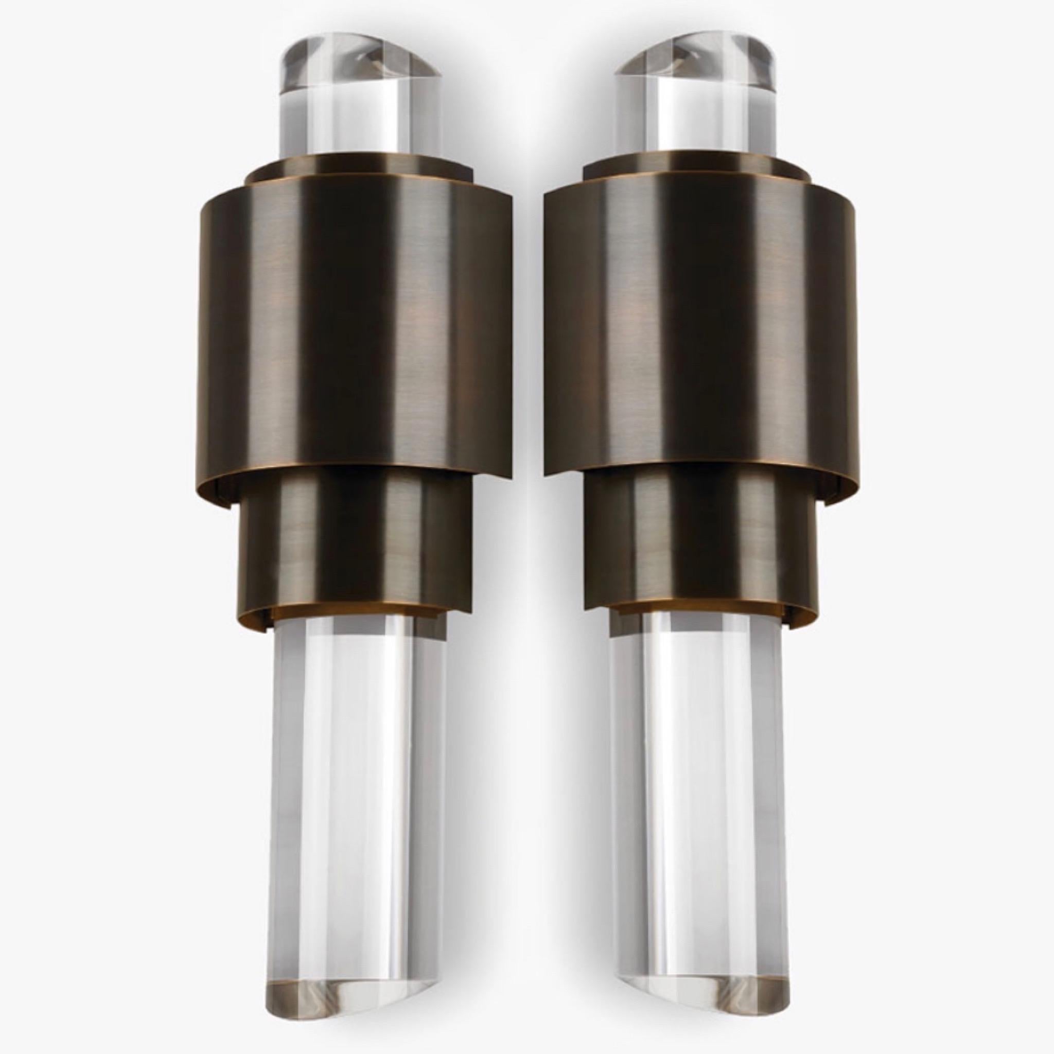 Pair of contemporary Art Deco style sconces with skyscraper design comprised of bronze metal frames and fitted with solid lucite columns. The lucite columns have slanted ends which work as prisms to reflect the light from the central frame. The