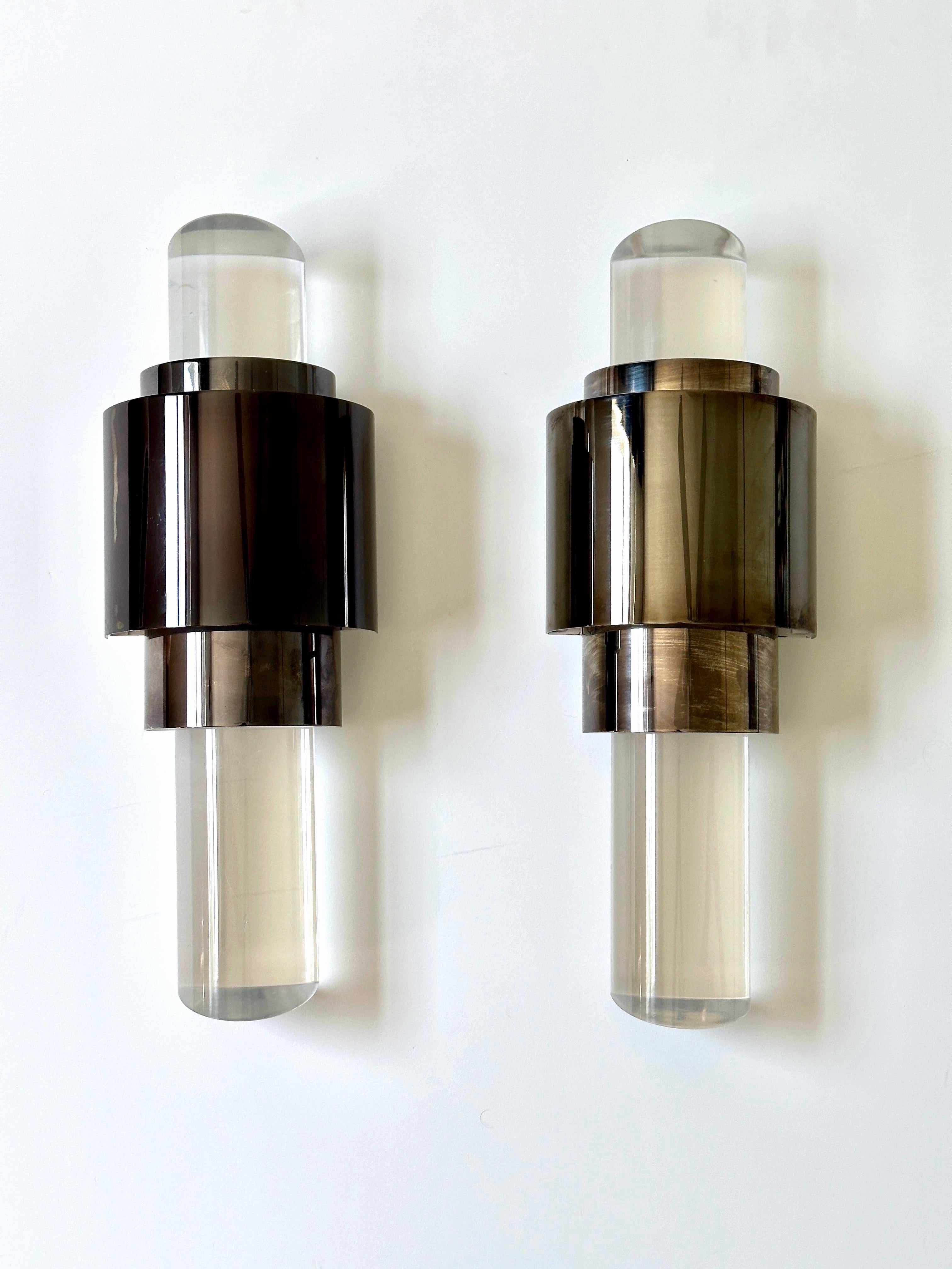 Pair of contemporary Art Deco style sconces with skyscraper design comprised of bronze metal frames and fitted with solid lucite columns. The lucite columns have slanted ends which work as prisms to reflect the light from the central frame. The