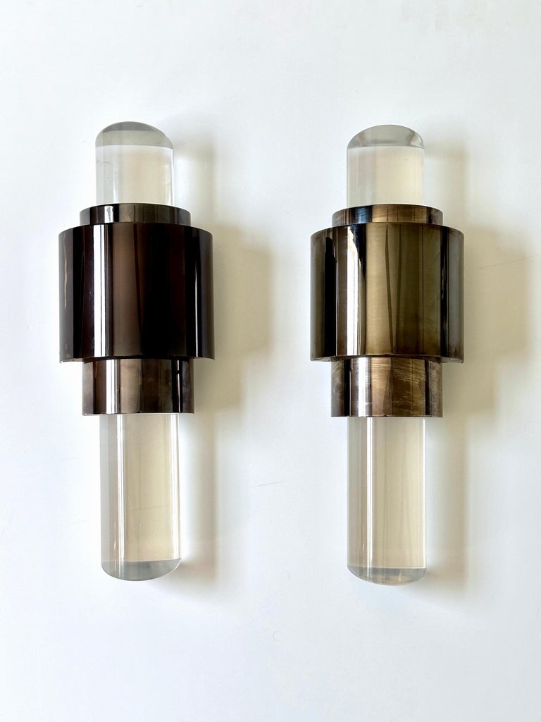 Pair of contemporary Art Deco style sconces with skyscraper design comprised of bronze metal frames and fitted with solid lucite columns. The lucite columns have slanted ends which work as prisms to reflect the light from the central frame. The