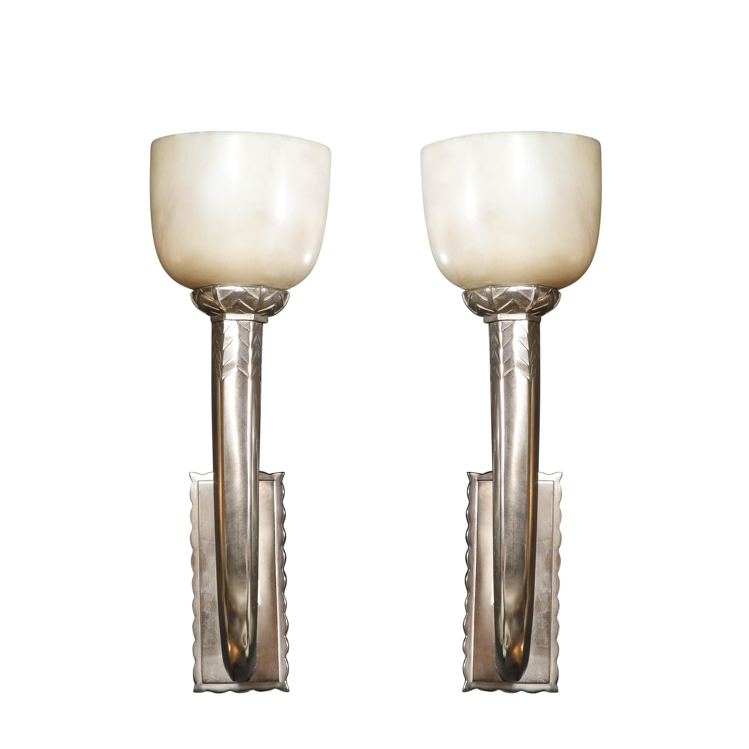 This elegant and balanced Pair of Art Deco Skyscraper Style Silvered Bronze and Alabaster Sconces originate from France, Circa 1935. They feature silvered bronze frames in a classic composition adorned with stylized geometric skyscraper detailing.