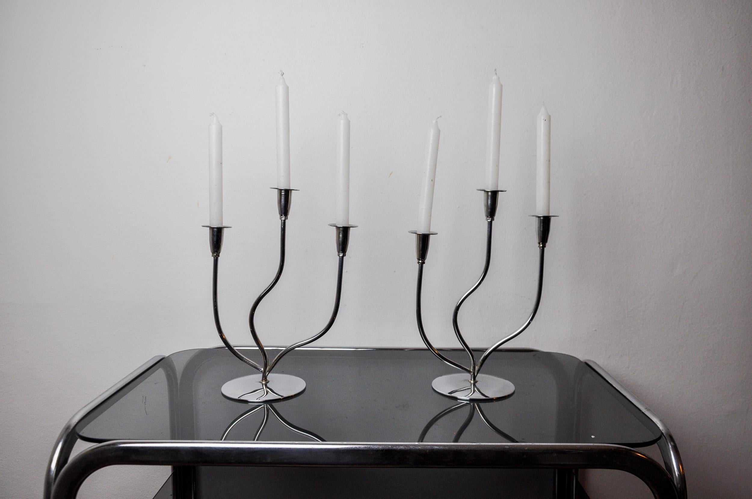 Sehr schönes Paar Kerzenhalter aus rostfreiem Stahl im Art-Deco-Stil, entworfen und hergestellt in Spanien in den 1970er Jahren. Struktur aus rostfreiem Stahl 18/8, die 3 Kerzen aufnehmen kann. Hervorragendes Designobjekt, das Ihr Interieur