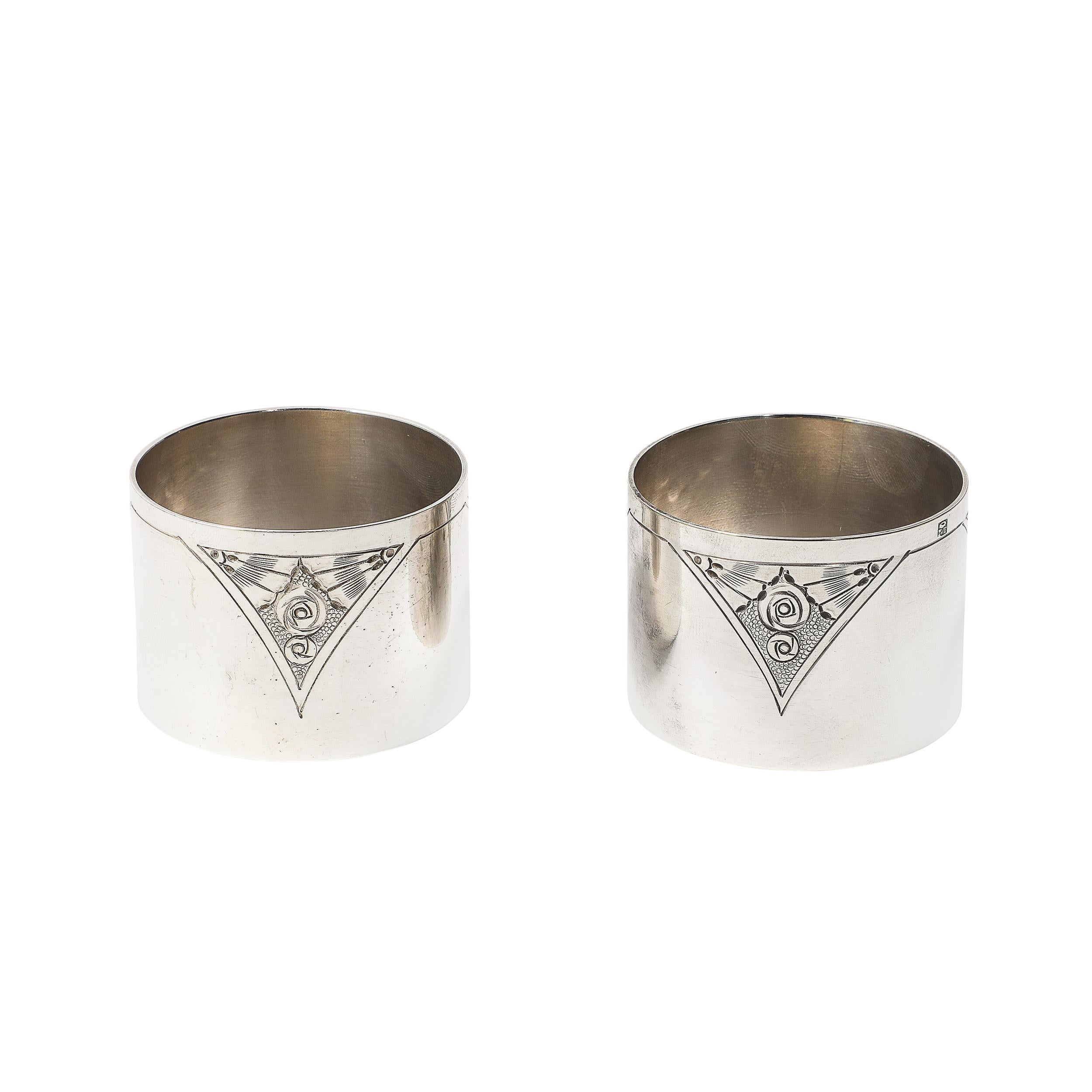 Questa raffinata coppia di portatovaglioli in argento sterling con marchio, realizzati in Inghilterra nel 1925 circa, presenta un esclusivo motivo cubista floreale cesellato. L'intricato design combina elementi floreali tradizionali con un moderno