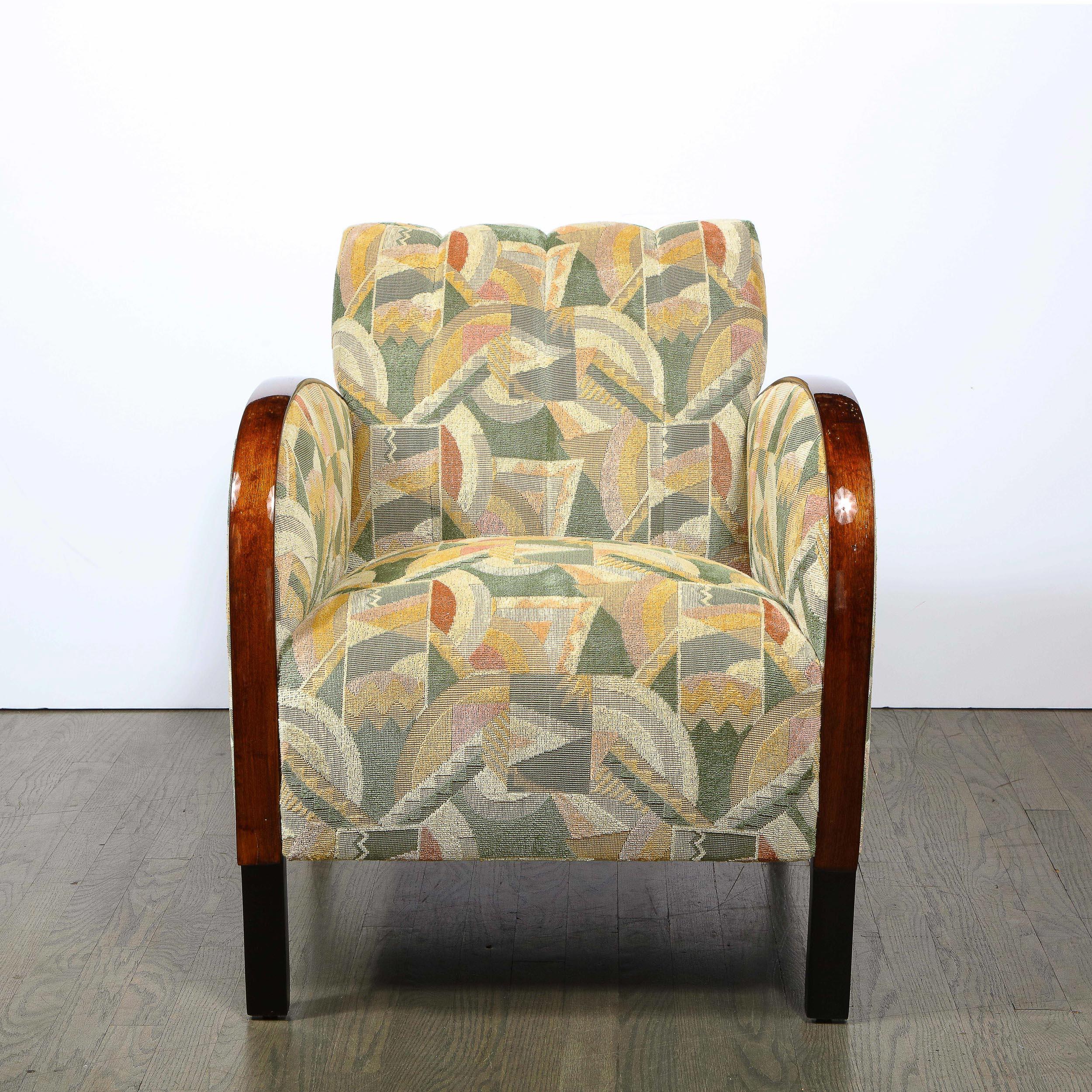 This stunning pair of Art Deco club/ arm chairs were realized in France, circa 1930. They feature streamlined arms; volumetric rectangular front legs; and slightly arched hind legs all in lustrous walnut. The chairs have been newly reupholstered in