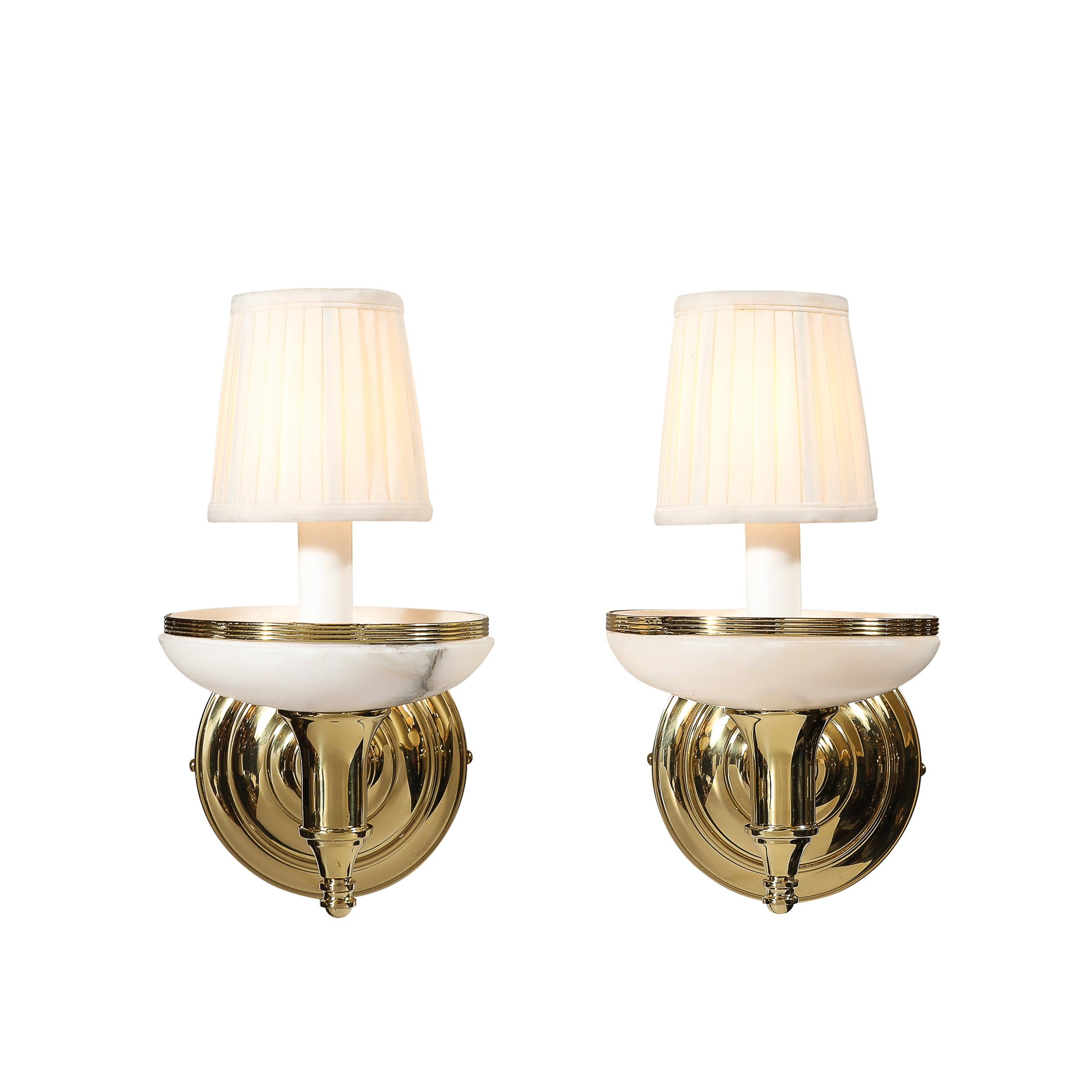 Questa affascinante coppia di lampade in stile Art Déco in alabastro e ottone lucido proviene dall'Italia del XX secolo. Presentano paralumi composti da alabastro intagliato con eccellenti dettagli venati, illuminati dalla luce delle lampadine. I