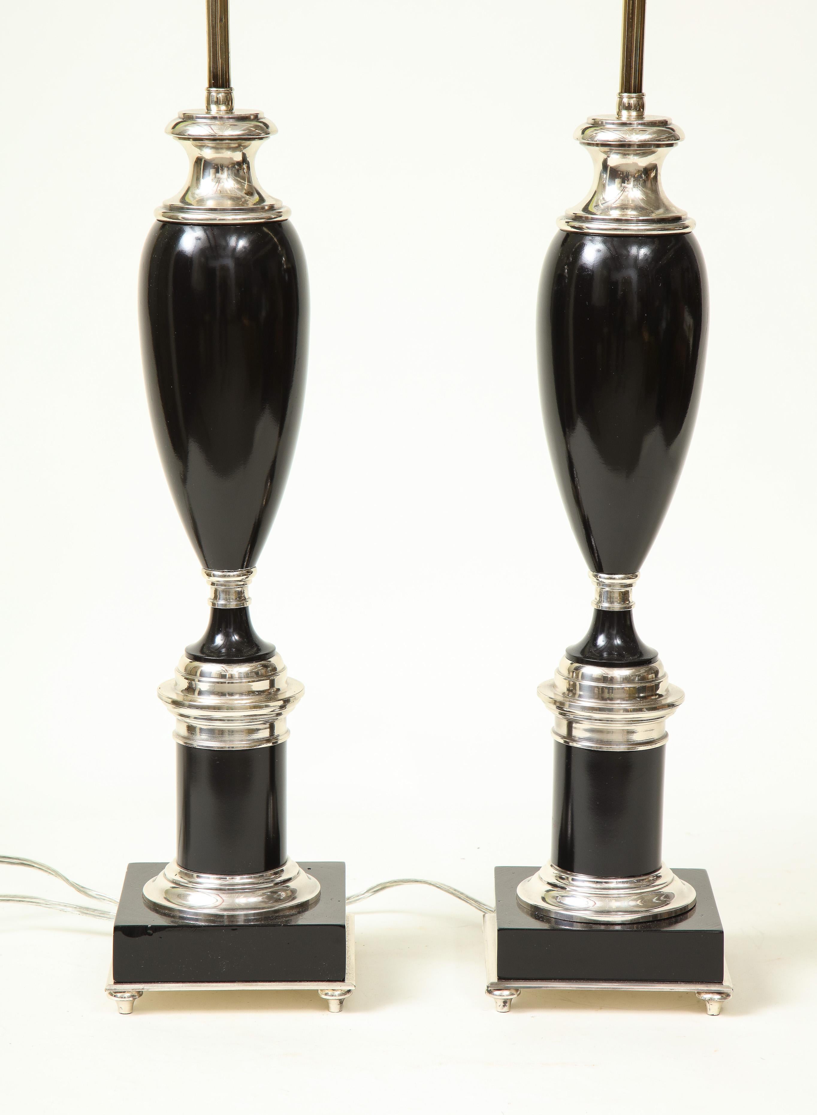 High style with each in the form of a black elongated footed urn on a plinth base, mounted with chrome details; fitted with two bulb sockets and adjustable rod.

Provenance: From the Collection of Mario Buatta, New York, NY.