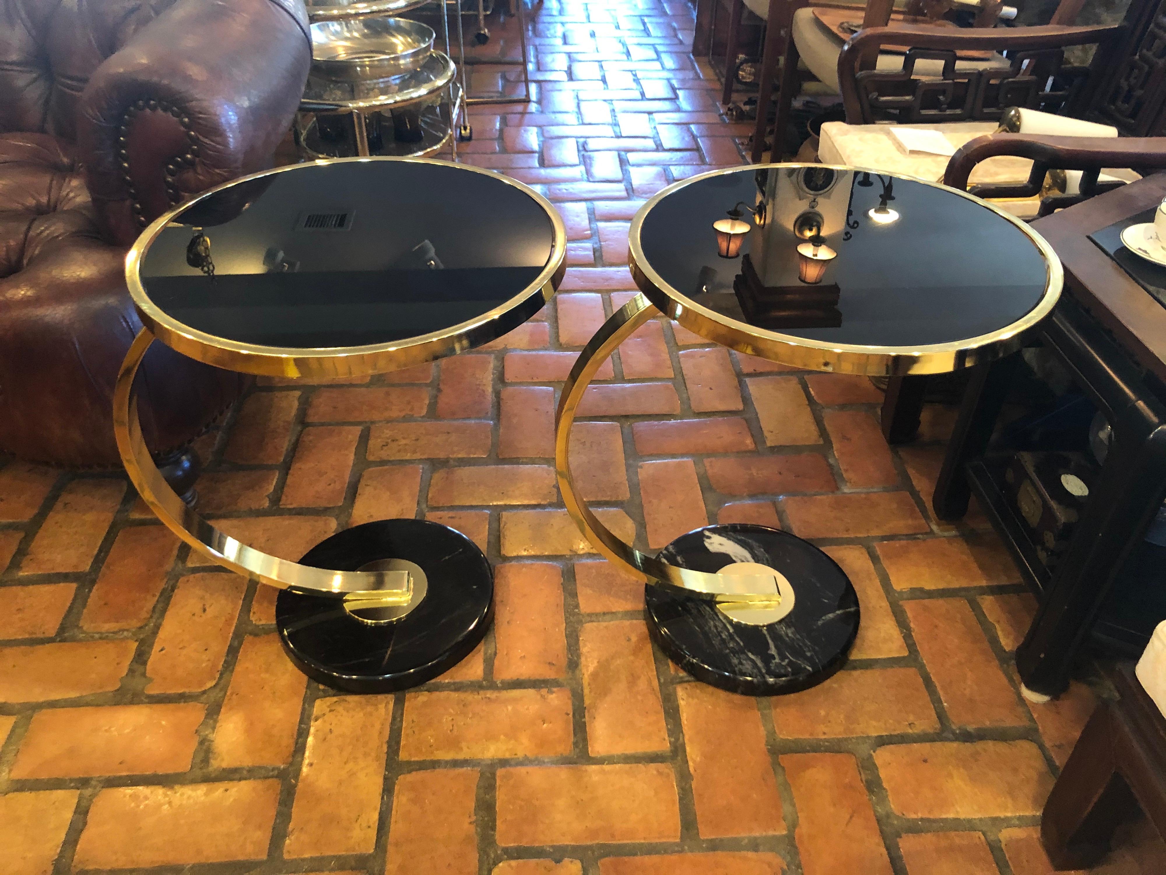 Pair of Art Deco style brass and black glass end tables. Round black marble bases with polished brass stems and black glass table tops. Sheer sophistication. Timeless design. Table top diameter is 18