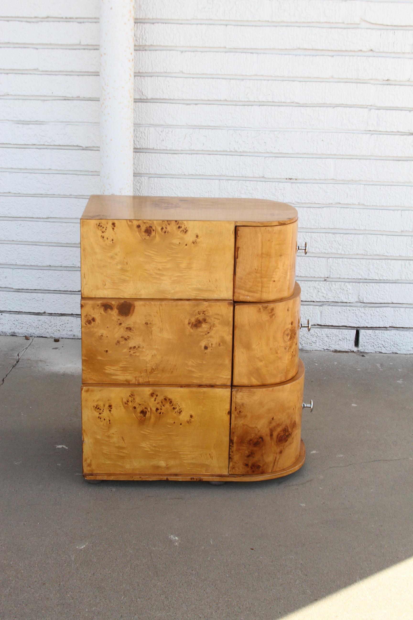 This is a beautiful pair of Art Deco Style chest. They're made of a burl wood and have 3 drawers for plenty of storage. The front is bowed giving them a demilune look. The drawers graduate in size.