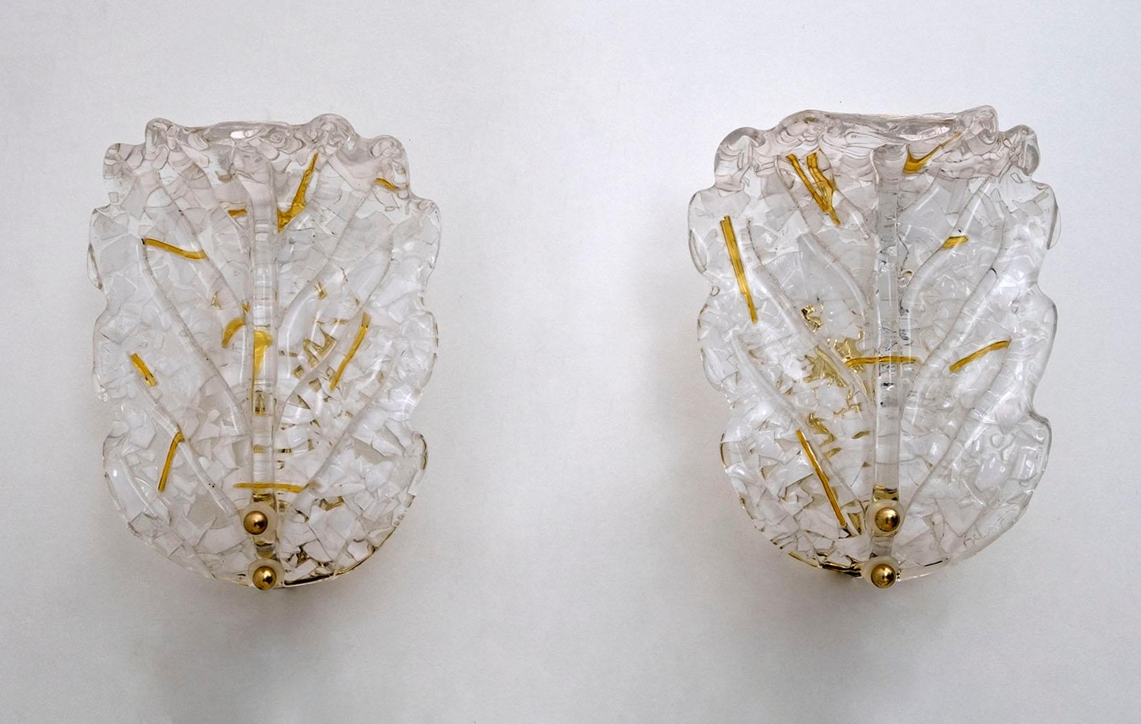 Pair of Italian Murano glass wall lights. Each wall lamp has a brass structure that supports a light bulb, shaded by a beautiful Murano glass grit leaf. Production of the 60s, in Art Deco style.