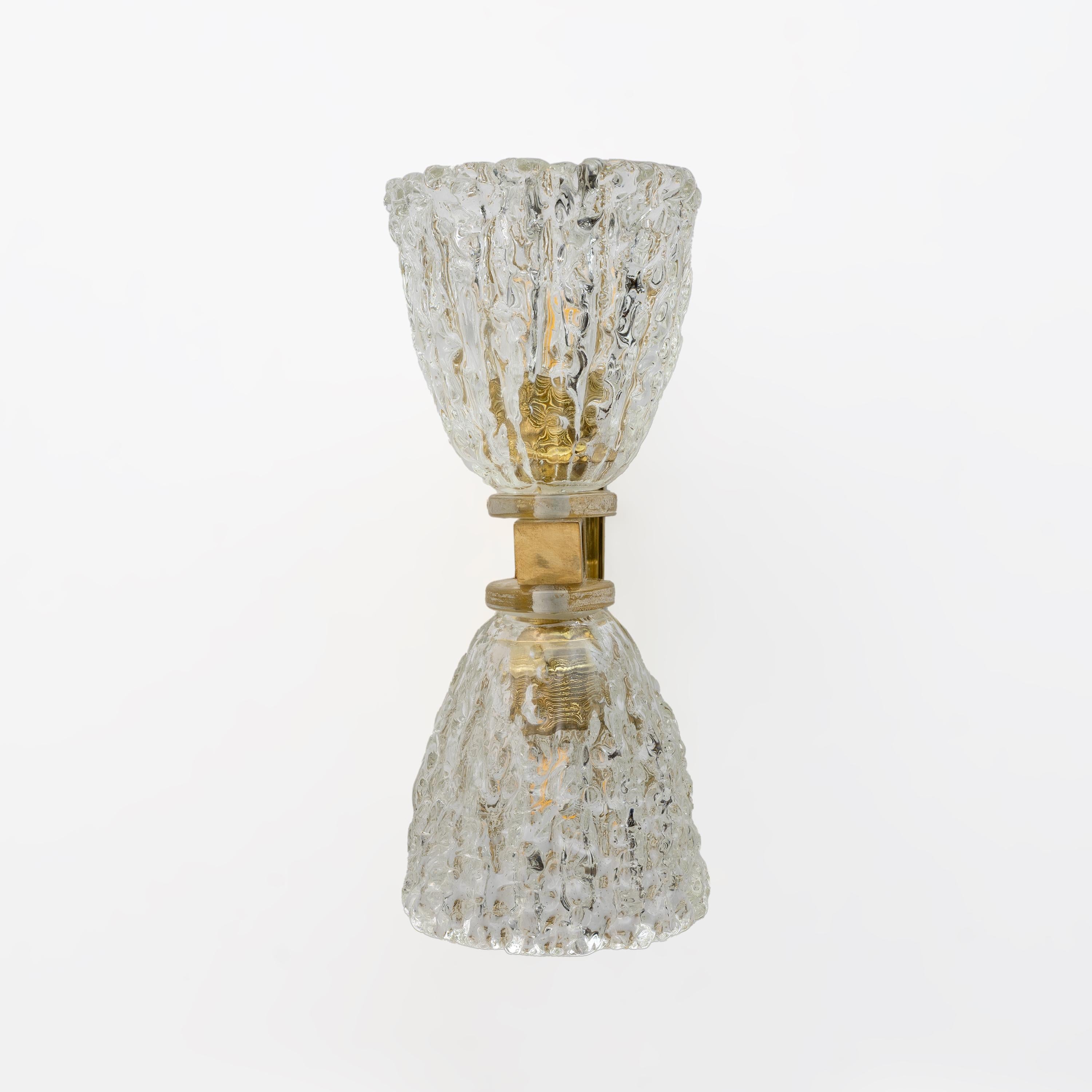 Una coppia di lampade da parete in stile Art Déco, con una doppia ciotola in vetro di Murano soffiato a mano e una struttura in ottone. Queste lampade altamente decorative sono adatte a qualsiasi ambiente. La loro luce è calda e piacevole, si