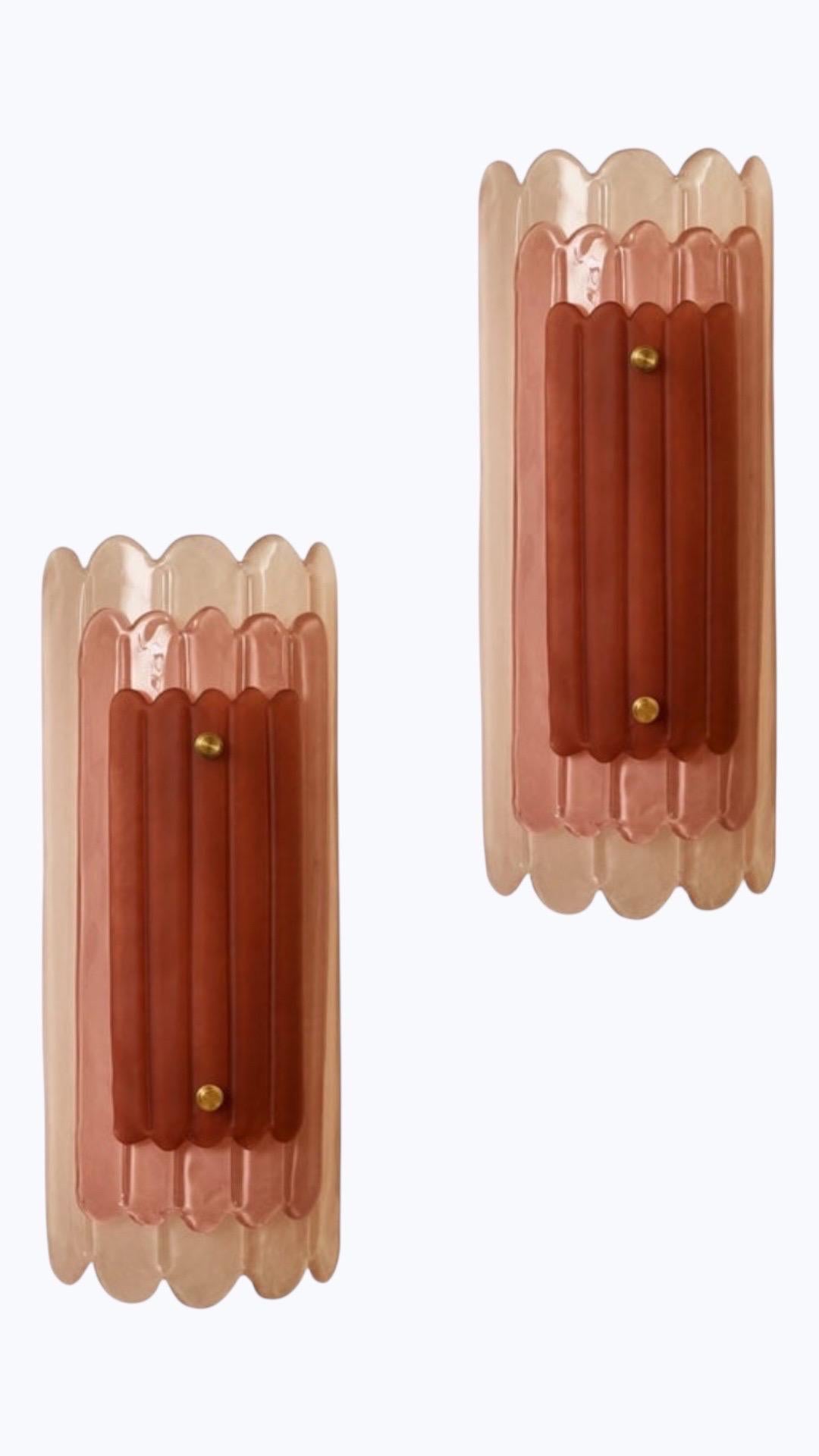 Paire d'appliques murales en verre de Murano rose de style Art Deco, en stock
Verres à 3 étages festonnés et texturés
3 verres teintés, 3 teintes de rose différentes
Raccords en laiton.
Verre de Murano texturé,
4 ampoules à douille Edison par