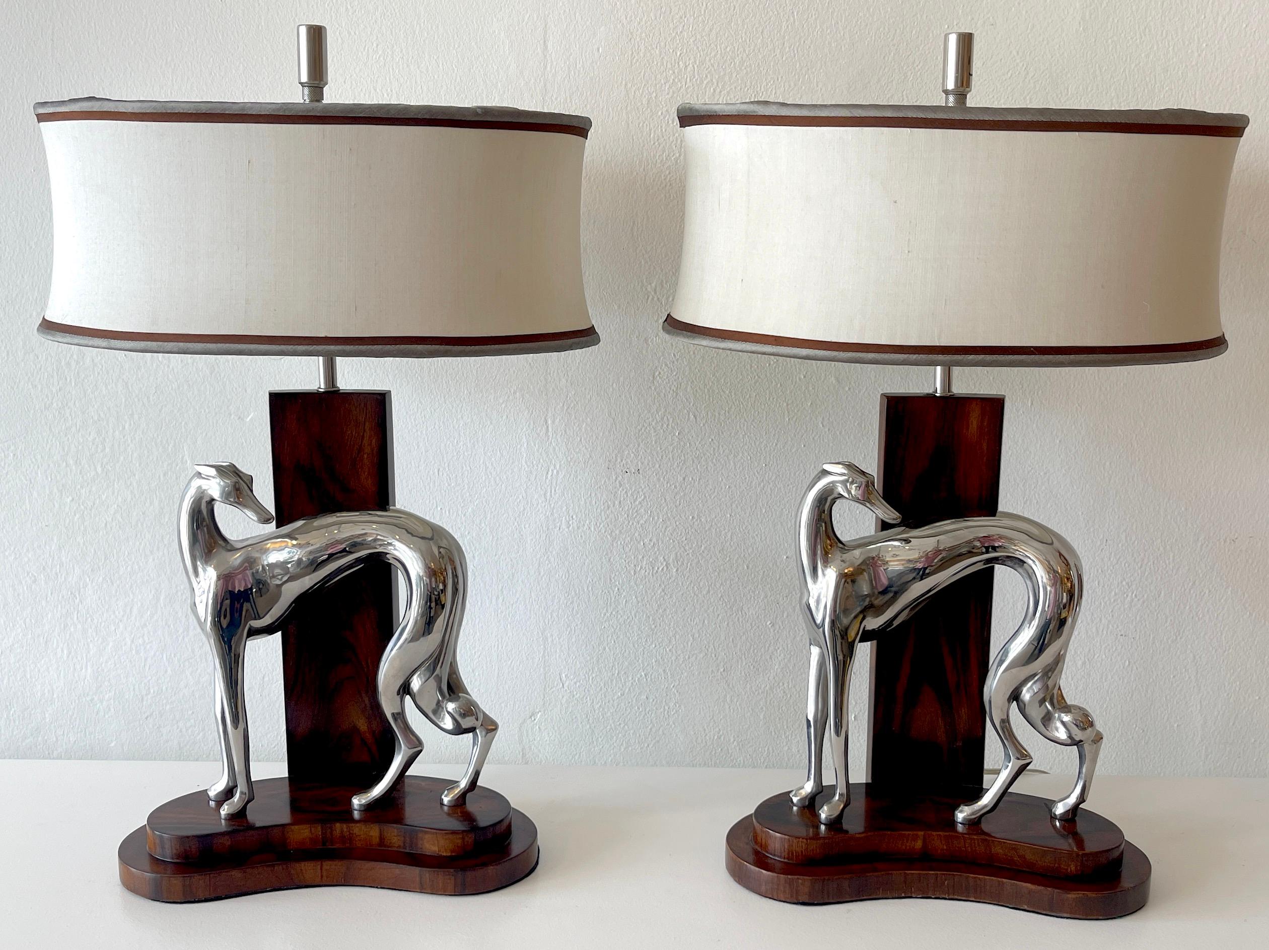 Pair of Art Deco style silverplated bronze whippet lamps with custom shades, Each one with French polished mahogany bases, A single standing figure of a Whippet, of exceptional quality and casting, the lamps are extremely heavy. Fitted with two