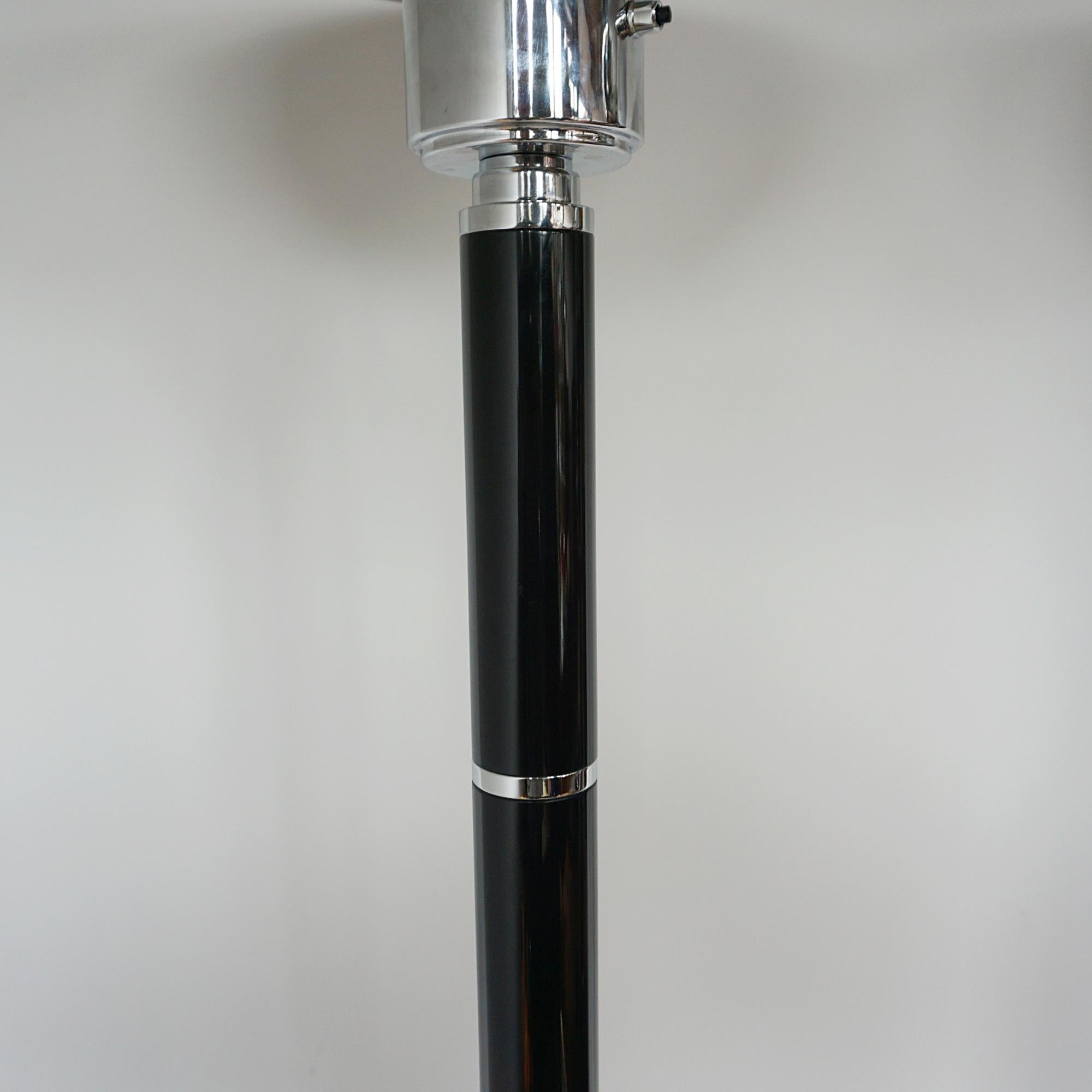 Ein Paar Stehlampen im Art-Deco-Stil. Schwarze Bakelitstiele mit verchromten Metallbändern, die zu einem verchromten Metallschirm führen. Auf einem runden Sockel aus verchromtem Metall. 

Abmessungen: H 172cm T des Sockels 32cm des Schirms