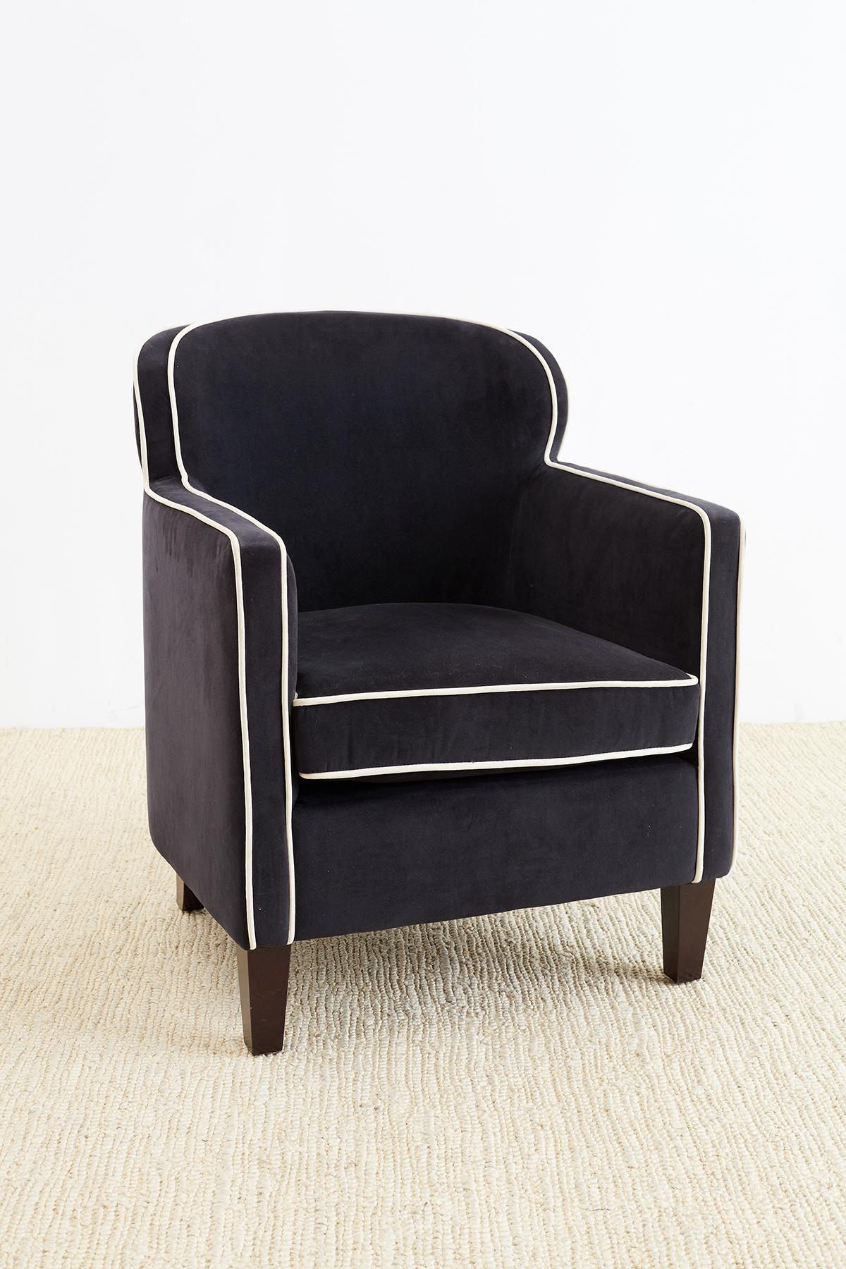 Suave pair of bespoke black velvet club chairs or lounge chairs made in the old Hollywood Art Deco style. Featuring a round back with an elegant profile that is accented by white piping. Each chair has a removable padded cushion and is supported by