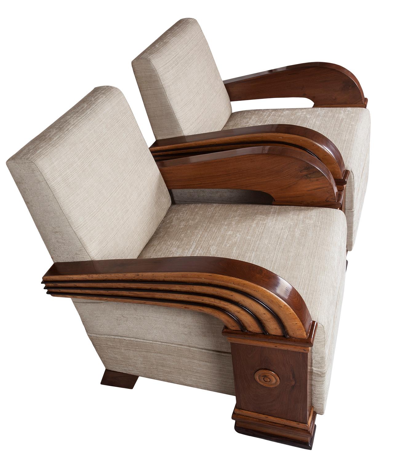 Pair of teak club chairs with rosewood accents in the art moderne streamlined style of the 1930s, epitomized in the sweep of the arms. European. Reupholstered with an off-white blend of silk and linen with two matching 16