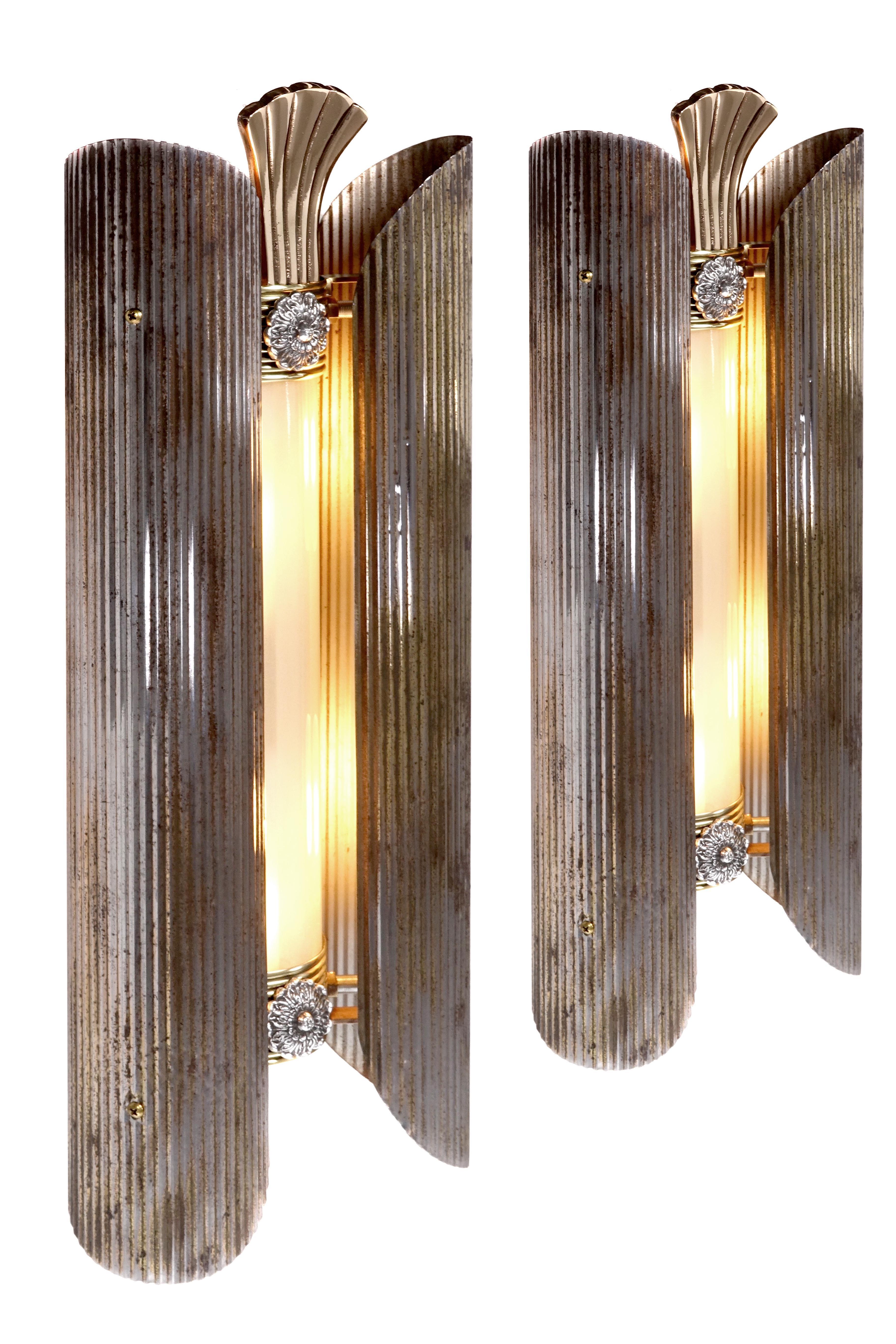 This is an interesting matching pair of high style theater side lights. They are well done with curved frosted cast glass panels with a fluted pattern. The side panels are rolled corrugated steel with a beautiful aged patina. They are priced and