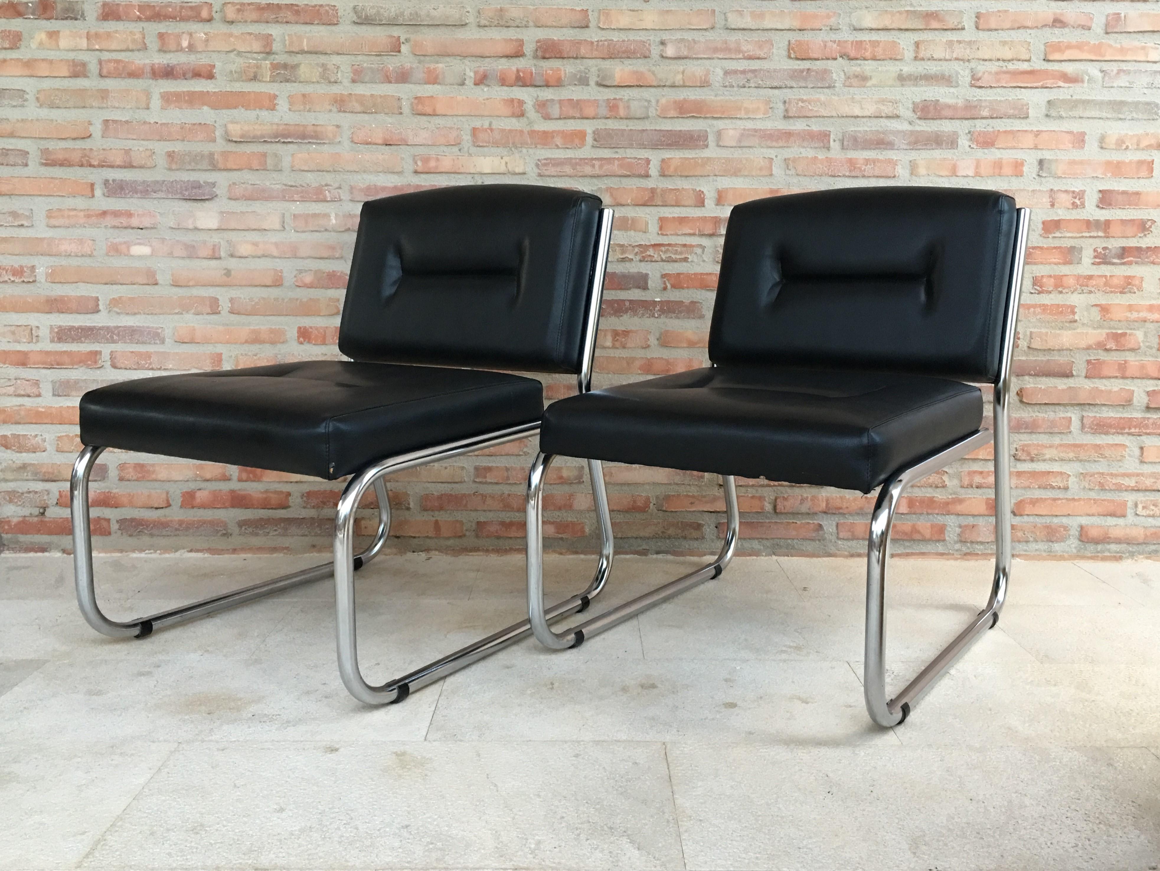 Mid-Century Modern pair of Art Deco tubular chrome lounge chairs in black leather.