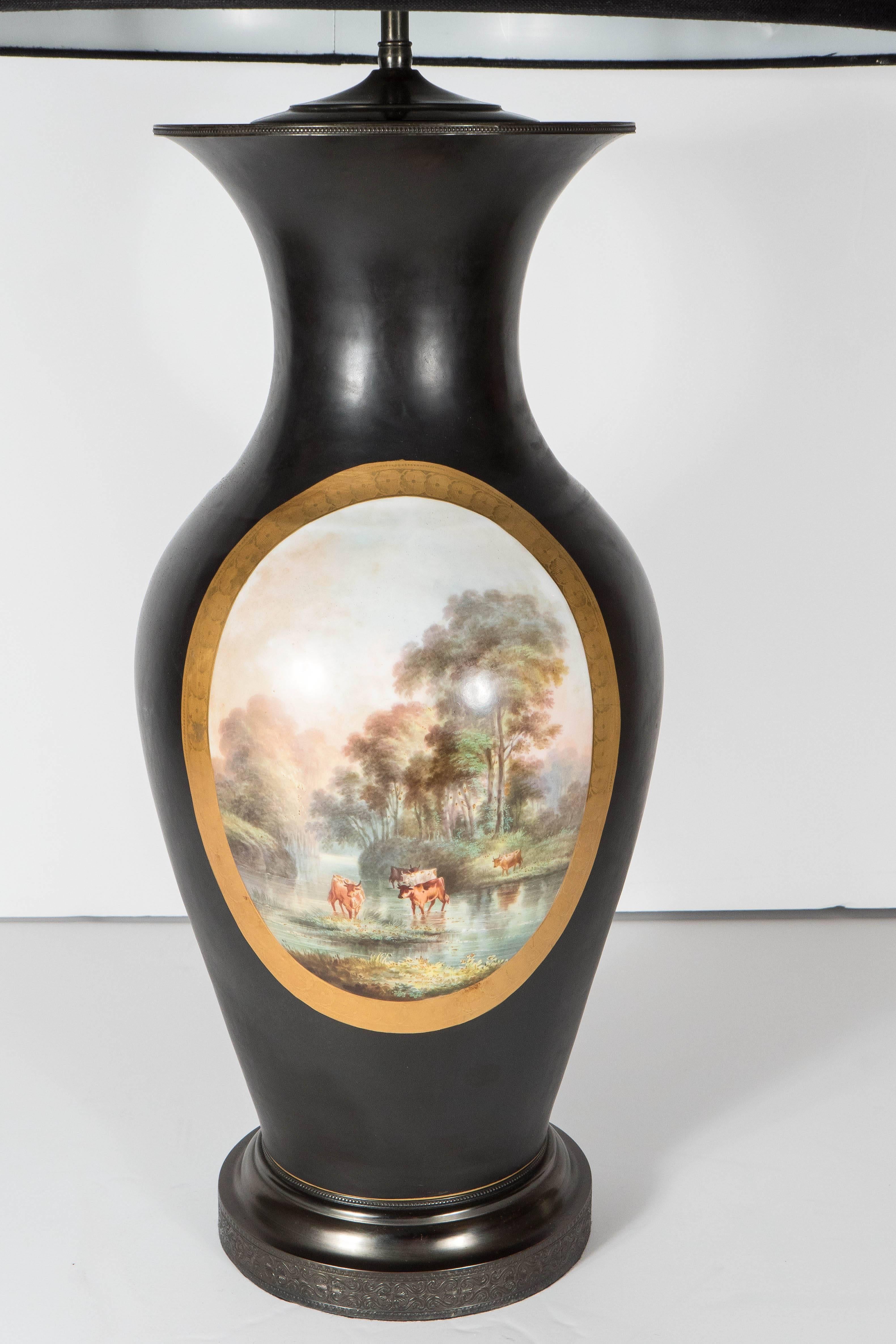 These elegant table lamps were created in England, circa 1945, repurposing antique vases from the early 20th century. The urn form matte black bisque finish bodies of the lamps feature oval medallions in the center, featuring pastoral scenes