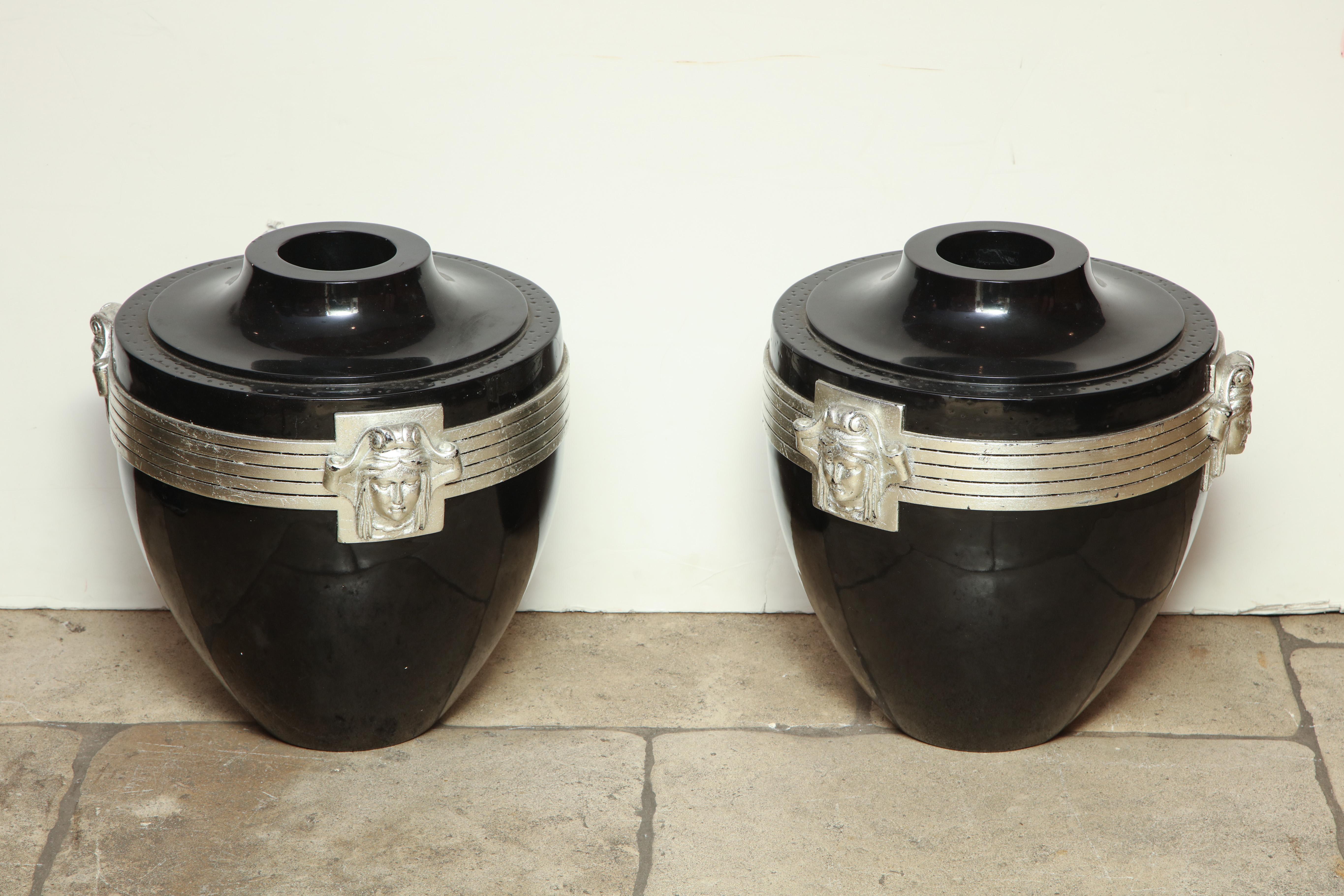Pair of Art Deco black lacquered urns with silver leaf decorated carved heads on each side.