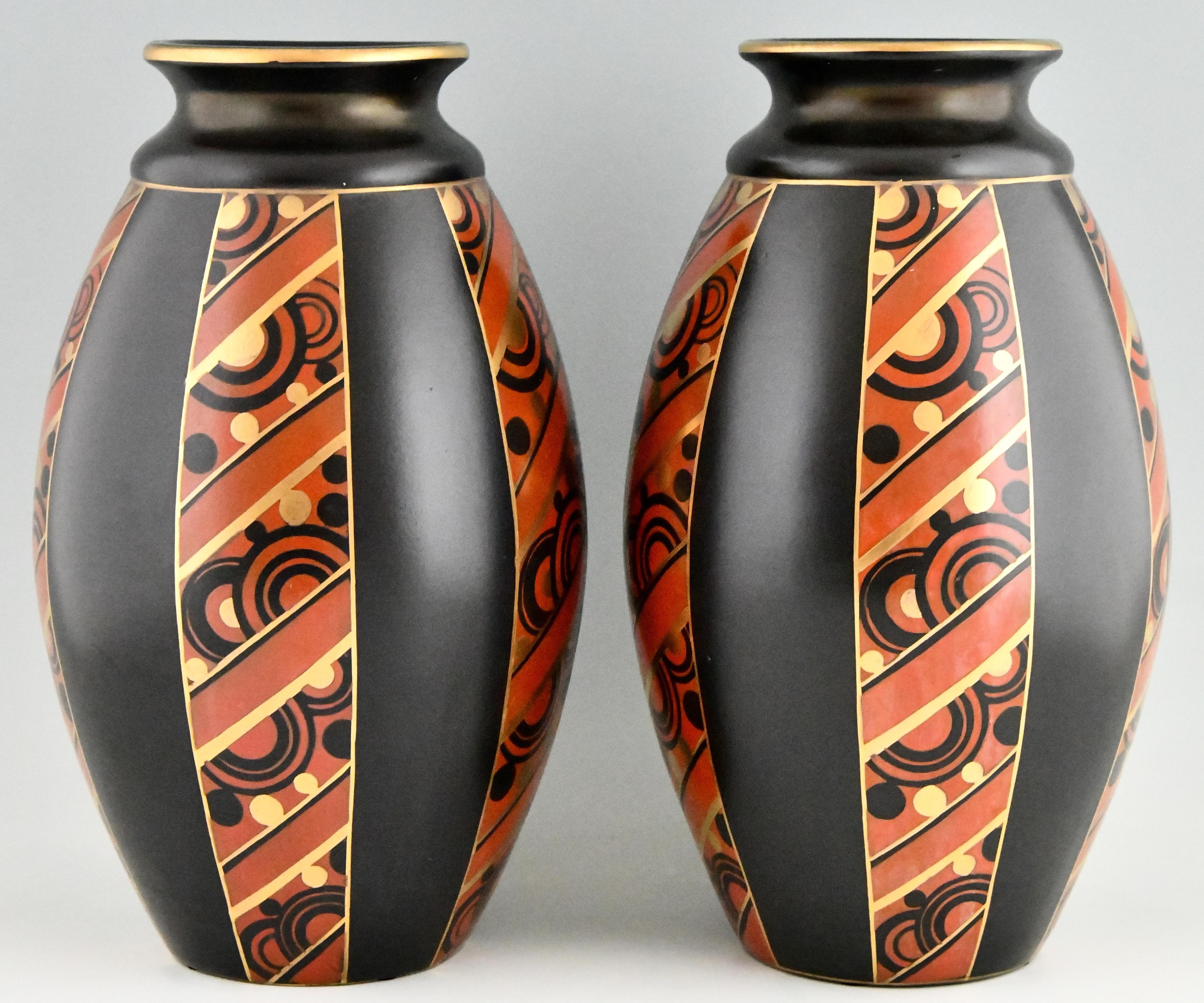 Beautiful tall pair of Art Deco vases with geometric pattern by Saint Ghislain. Black ceramic with red and gold Art Deco pattern.
Belgium 1930. 

Similar vases are illustrated in ?“Art Deco Belgique 1920-1940” ?Exhibition catalogue published by