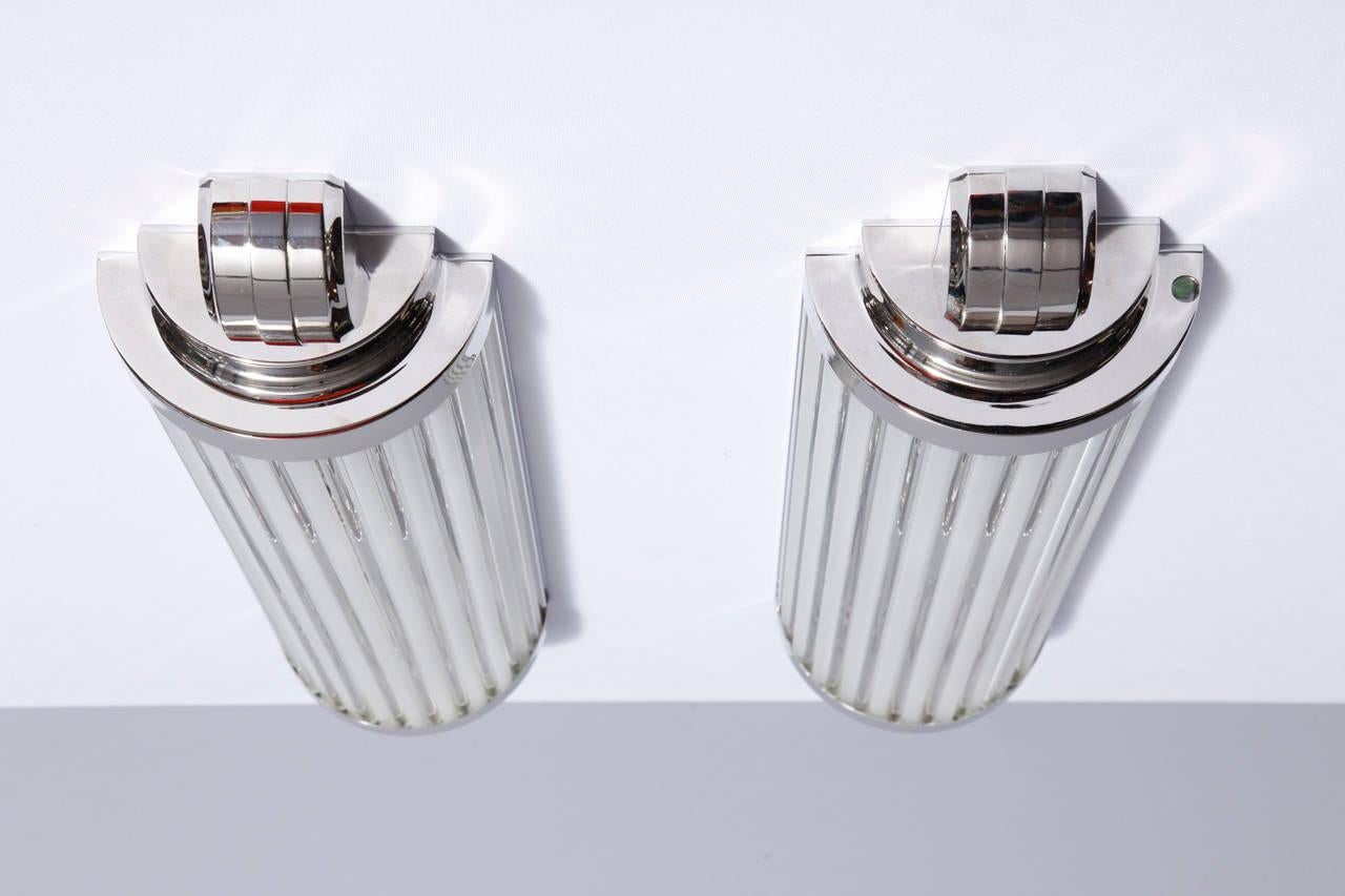 Ein einfaches Design mit weichen Formen. Ein Paar modernistische, vom Art-Deco inspirierte Scones aus vernickeltem Metall und Glasstäben. Originalentwurf von Atelier Petitot.
Sie können in verschiedenen Dimensionen angepasst werden.
