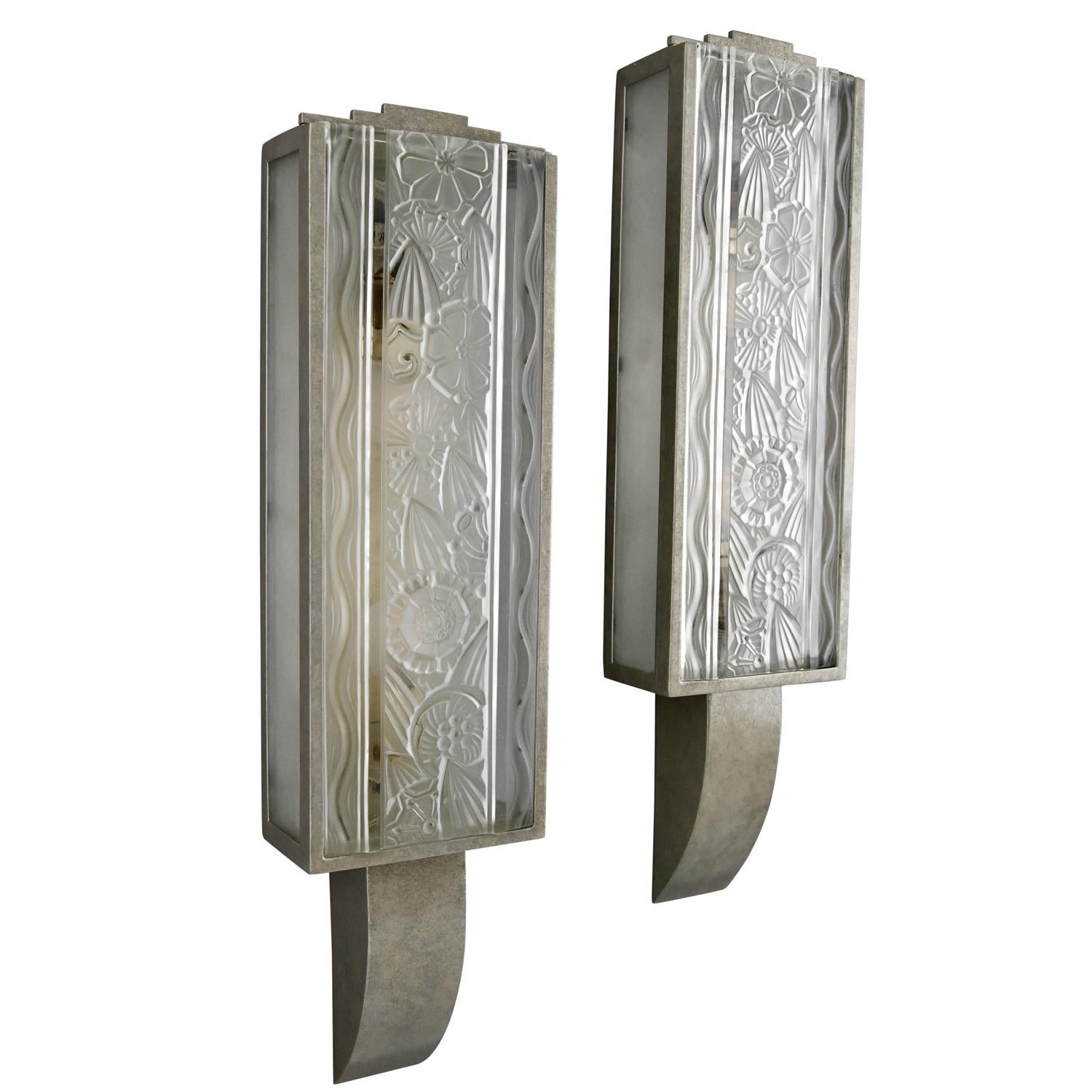 Pair of Art Deco wall sconces signed by Hettier & Vincent
Marked Made in France. Frosted glass panels with pattern of stylized flowers produced by Baccarat. 
Bronze frames, old silver patina. 

About Hettier & Vincent:
The association between the
