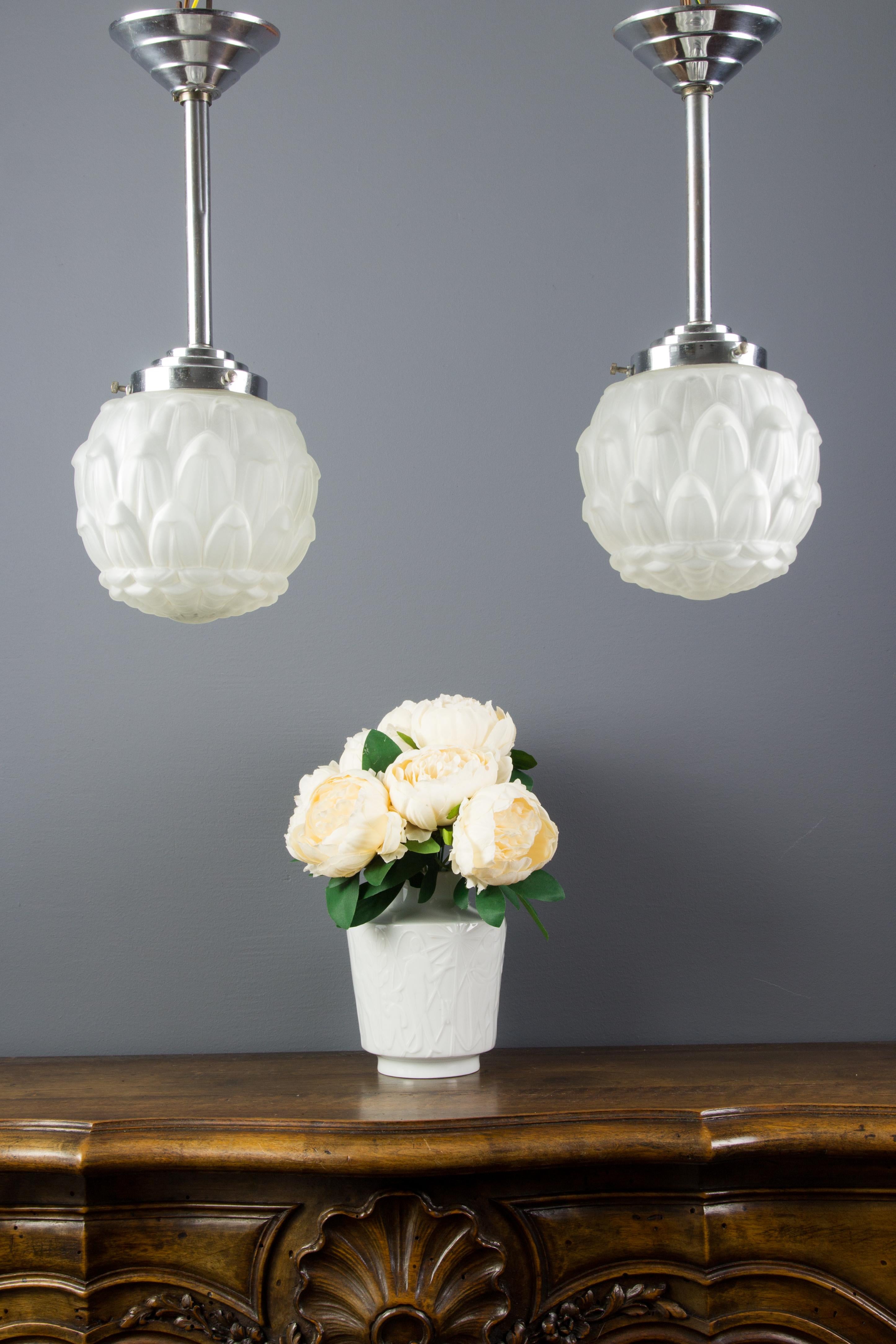 Beautiful set of two Art Deco frosted white glass and chrome / nickel-plated metal pendant ceiling lights, made in France in 1930s.
Each light fixture has one socket for the B22 size light bulb.
Dimensions: Height 40 cm / 15.74 in, diameter 15 cm /