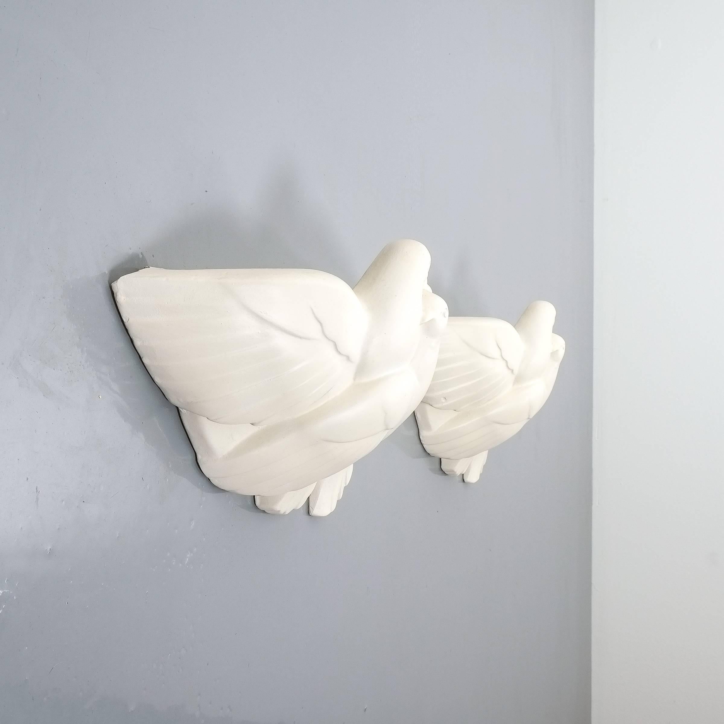 Pair of Art Deco white plaster dove sconces, France, circa 1935 (attr. Jacques Adnet). Rare pair of plaster wall lamps depicting some love birds. Uplight with one e14 bulb. One light shows a chip at the back (pictured) otherwise in excellent