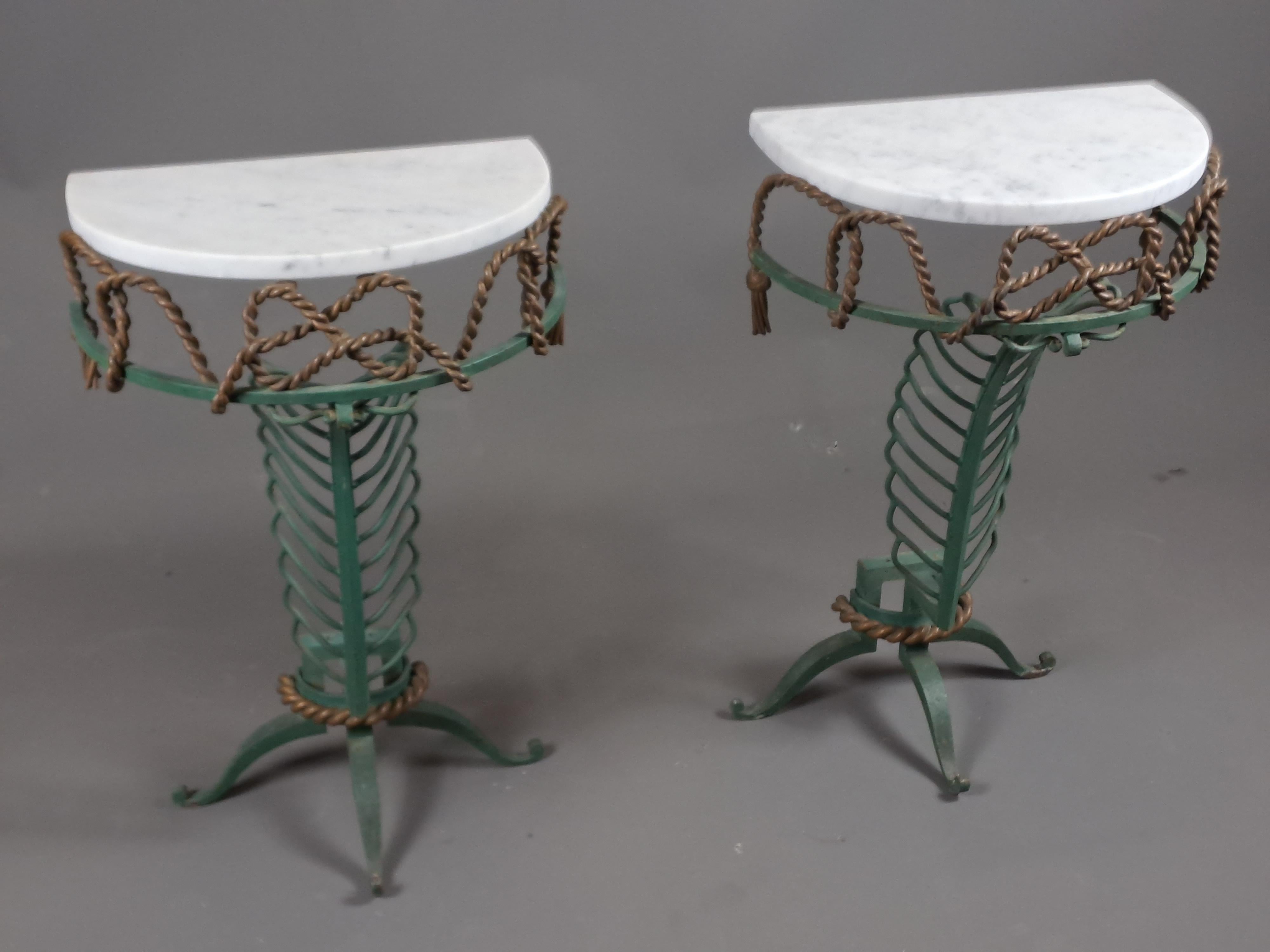 Lovely pair of small wrought iron consoles with double green and bronze patina, decorated with ribbed foliage and intertwined ropes.

Half-moon Carrara marble tops.

Beautiful creation attributed to Gilbert Poillerat, was part of a set including