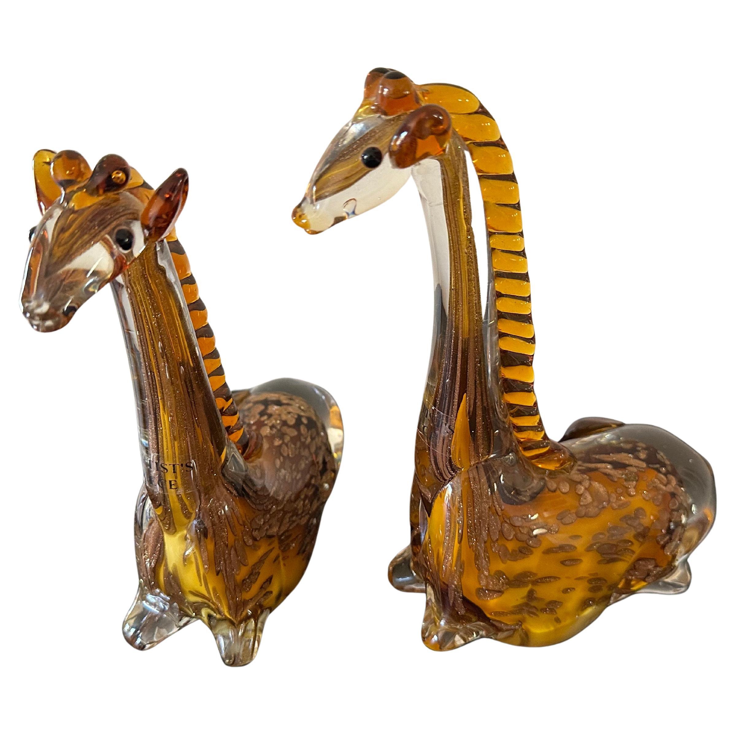 Paire de sculptures de girafes posées en verre d'art dans le style de Murano, vers les années 1980. Magnifique ensemble de sculptures de girafes en verre d'art colorées en ambre avec des tons plus foncés et plus clairs et des taches mouchetées de
