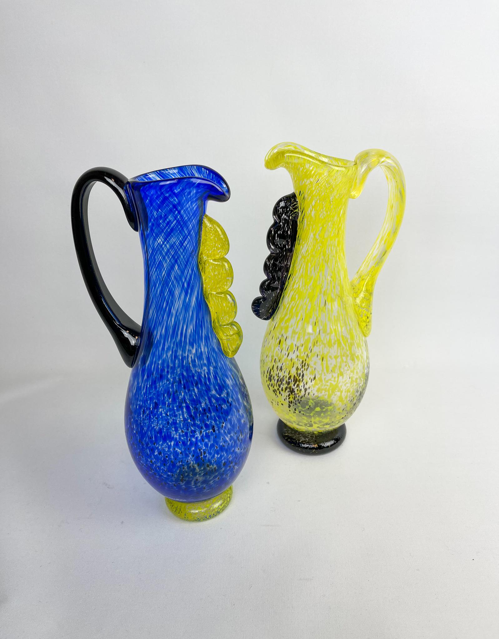 A pair of art glass vases designed by Ann Wåhlström for Kosta, Sweden. They both have lines and color that gives associations to the Swedish flag. Nicely sculptured and can be used as a jug, vase or of course just in decorations purpose.

Nice