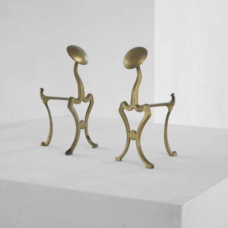 Pair of Art Nouveau Andirons or fire dogs in patinated brass, first half of the 20th century.   Whimsical pair of andirons in patinated brass from early 20th century. Very stylish pair of andirons / fire dogs for your fireplace, or to use just as