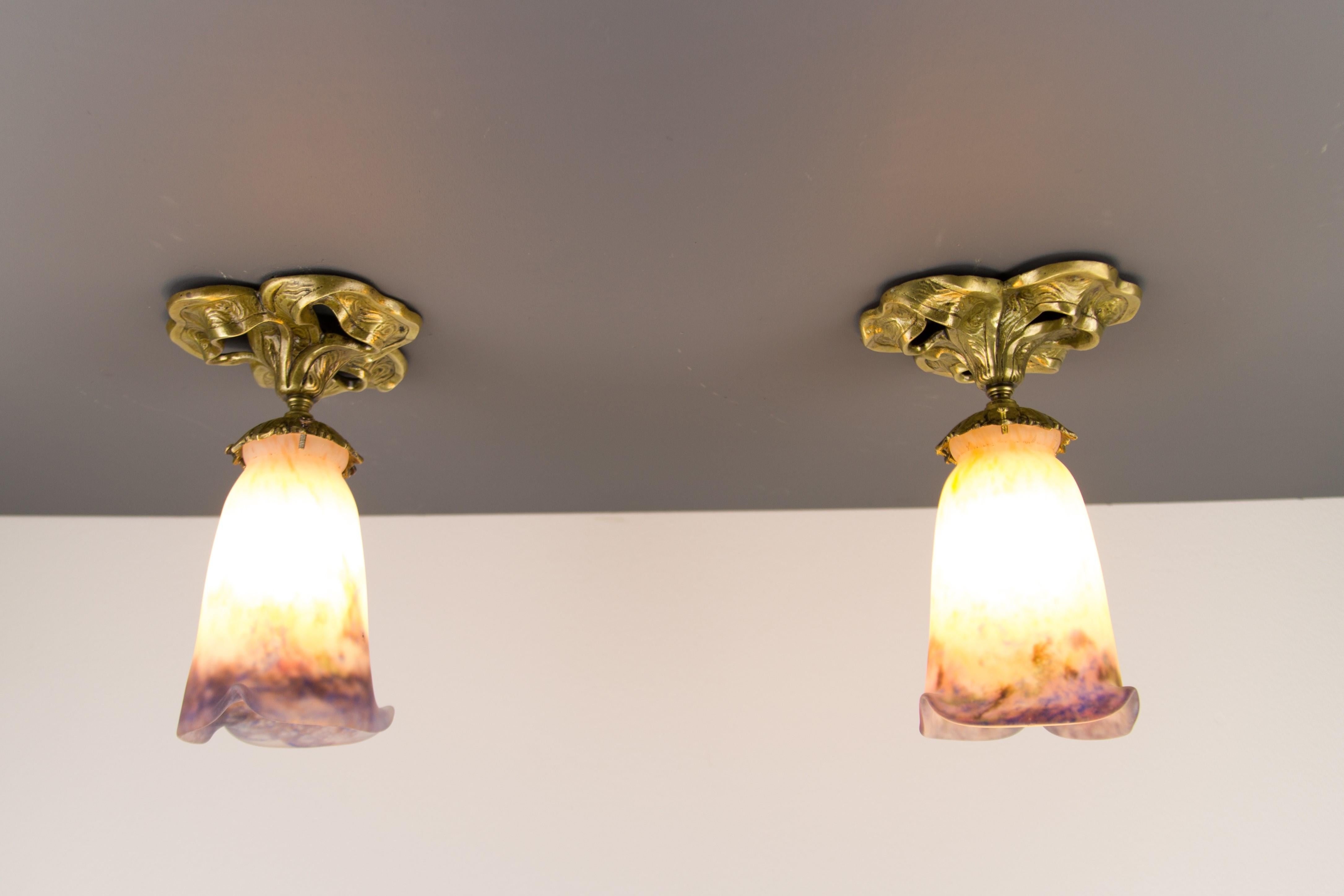 A beautiful pair of Art Nouveau bronze ceiling lamps with pâte de Verre glass shades signed Muller Frères Luneville in cream, blue, purple, and green color.
Each light fixture has one socket for the B22 size light bulb.
Dimensions: height 22 cm /