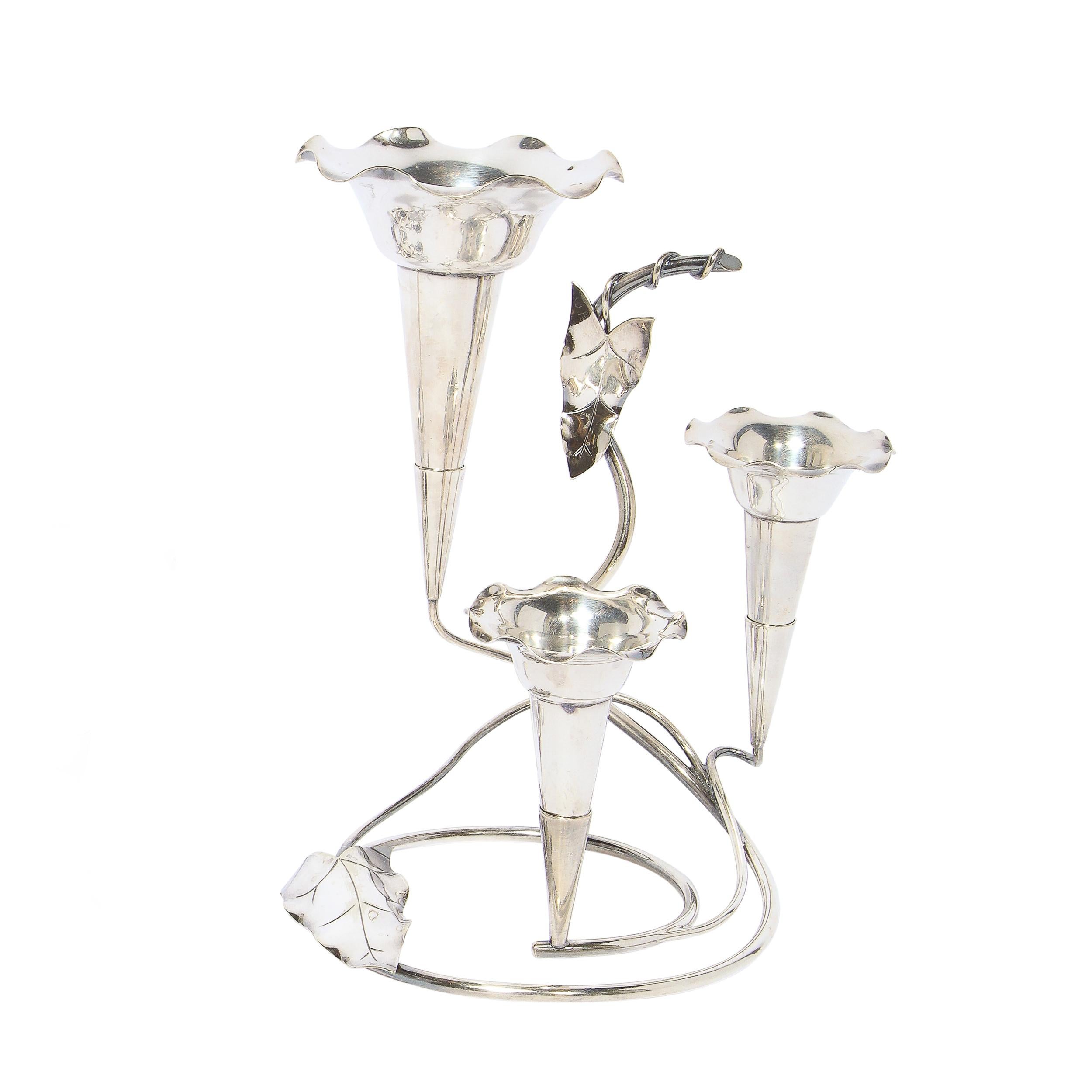 This stunning and graphic pair of Art Nouveau candleholders were realized in the United Kingdom circa 1905. The larger features three trumpet candleholders each with swirling bases and stylized foliate detailing suggesting morning glory leaves and